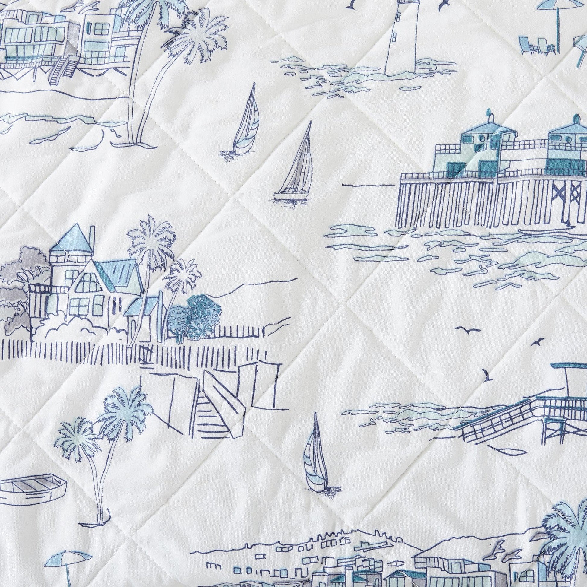 Quilt with blue coastal scene patterns on a white background