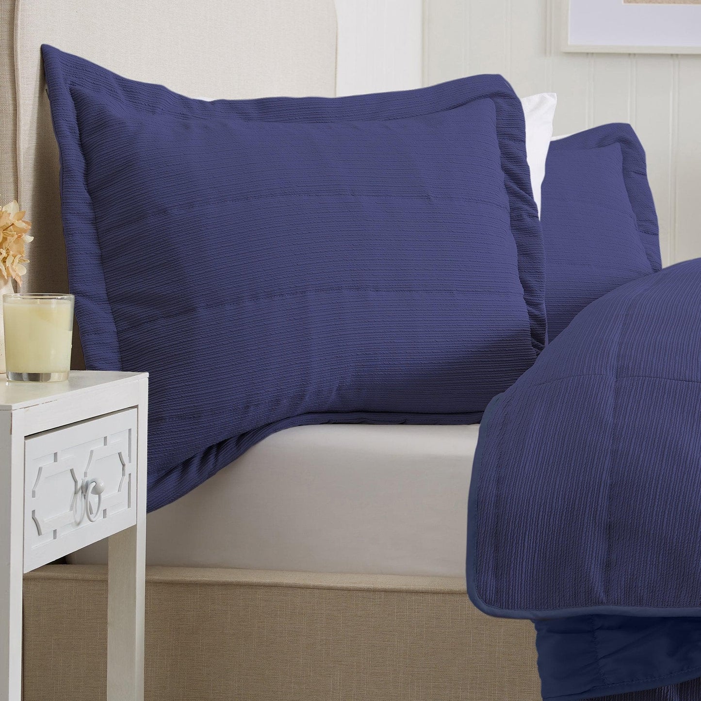 Navy blue bedding set on a bed with a white nightstand.