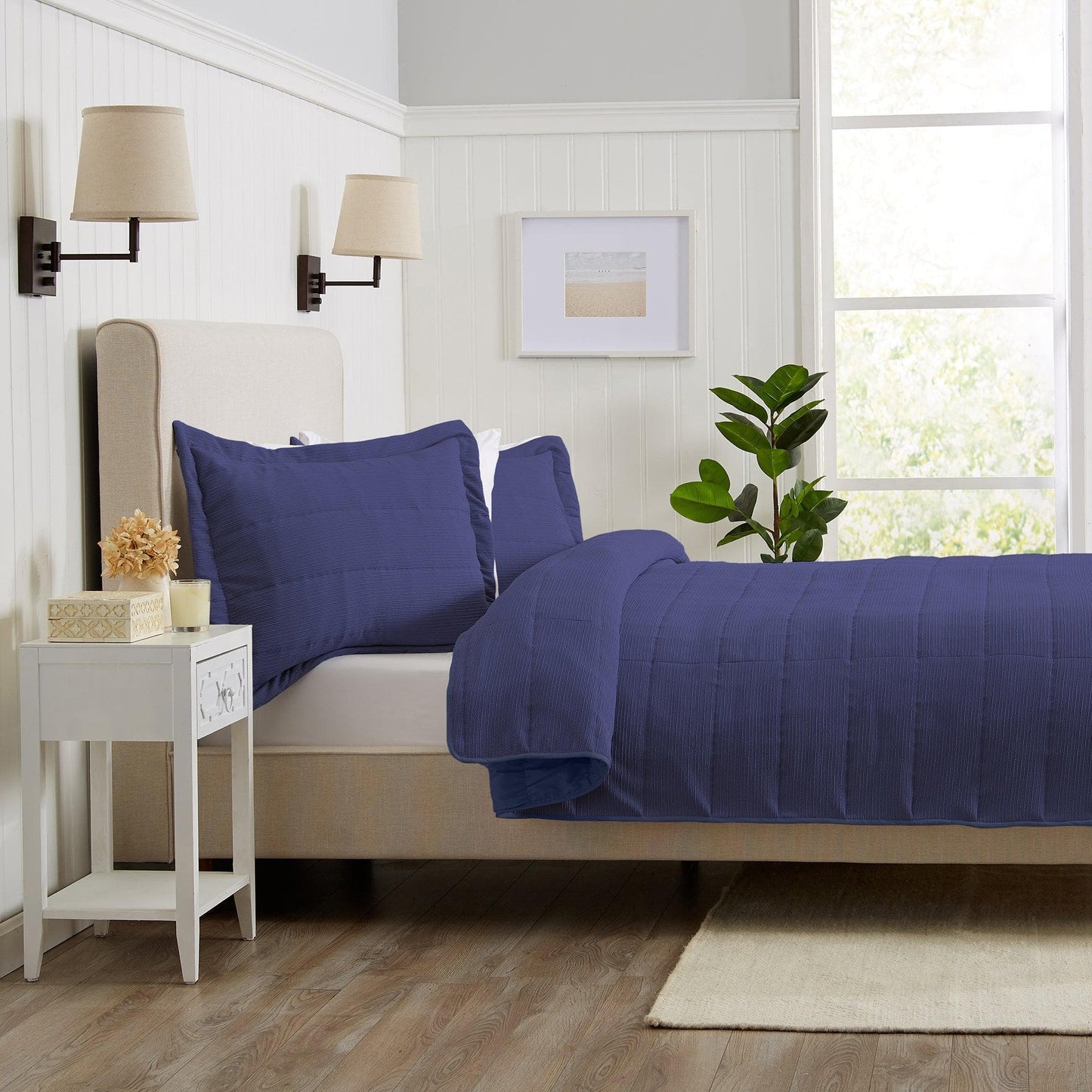 Bedroom with a bed covered in blue bedding, nightstand, and lamp.