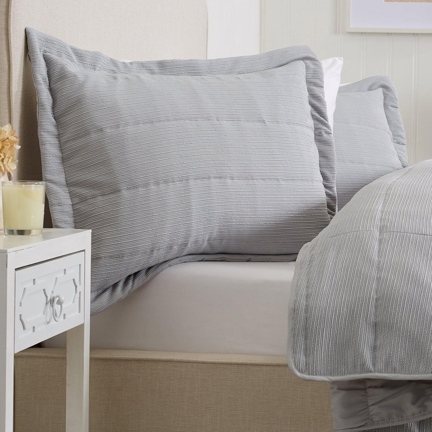 Gray striped bedding set on a bed with a nightstand in the foreground.