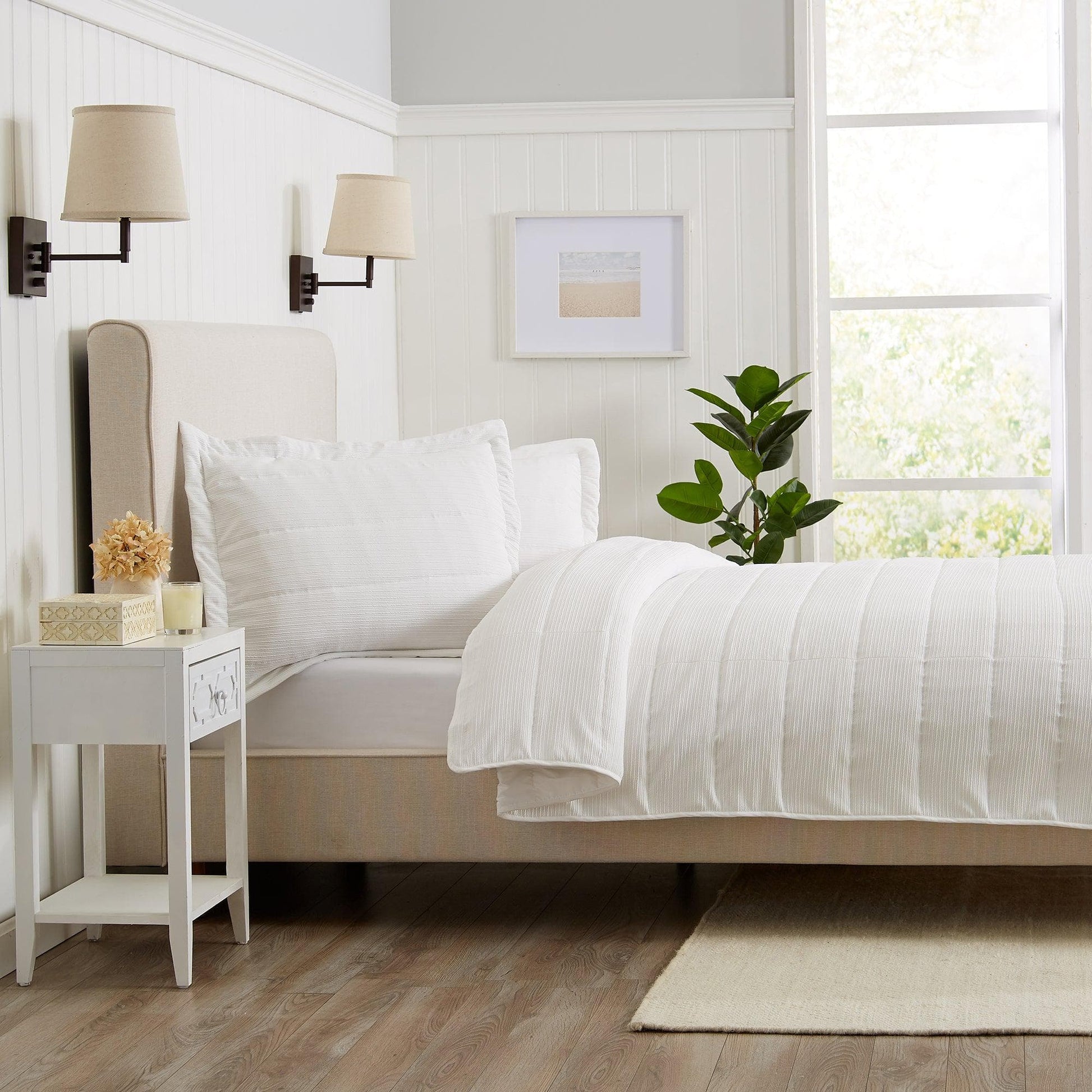 Neatly made bed with white bedding in a bright bedroom.