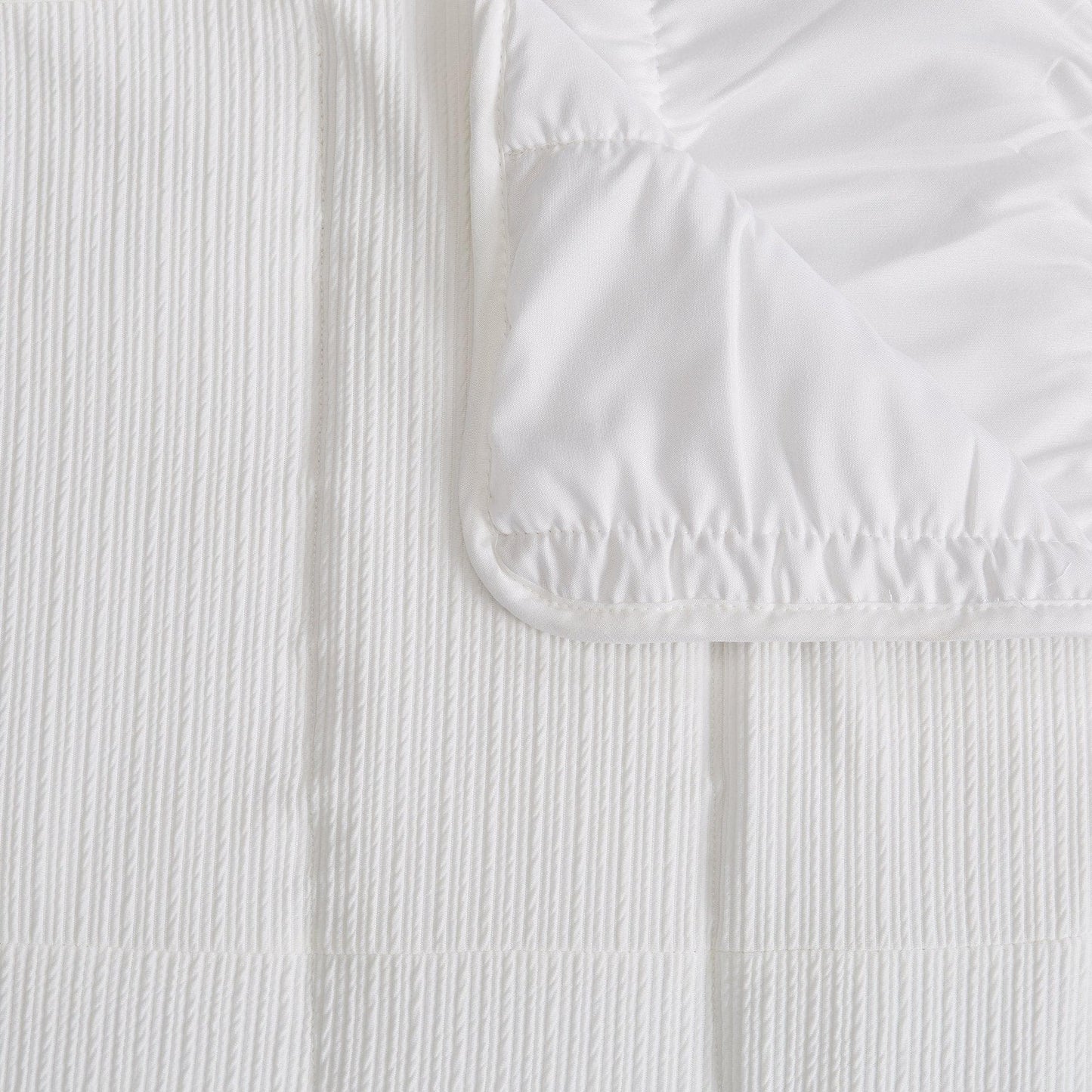Close-up of a textured white quilt on a matching fabric background
