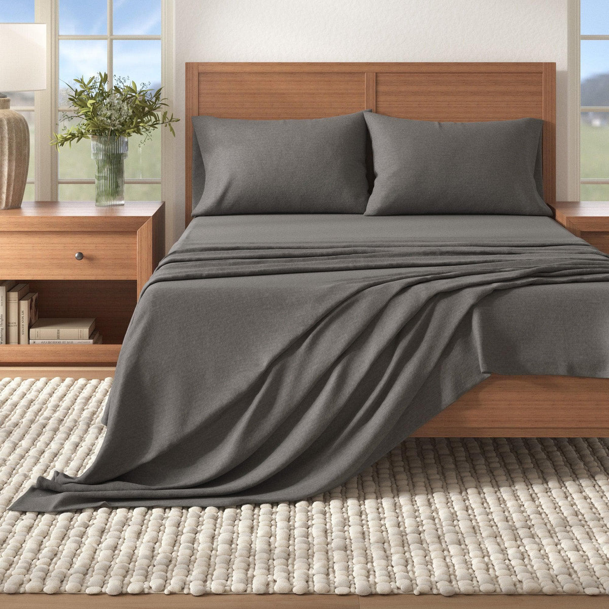 Gray bedding set on a wooden bed in a bedroom with a window in the background.