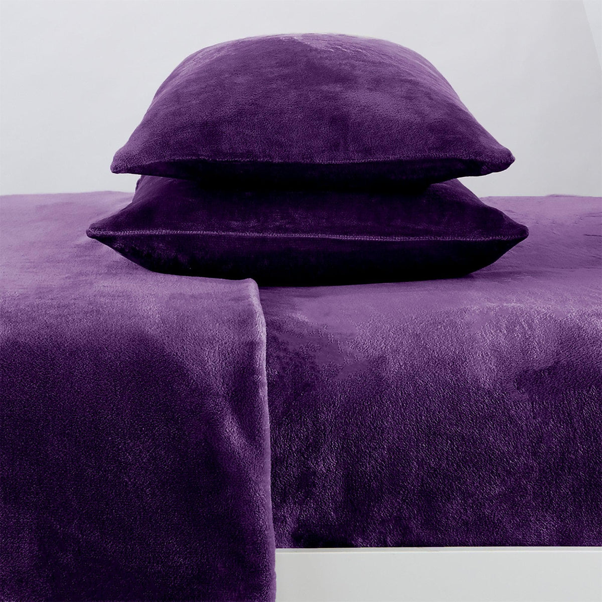 Purple textured bed sheets and pillows on a plain background