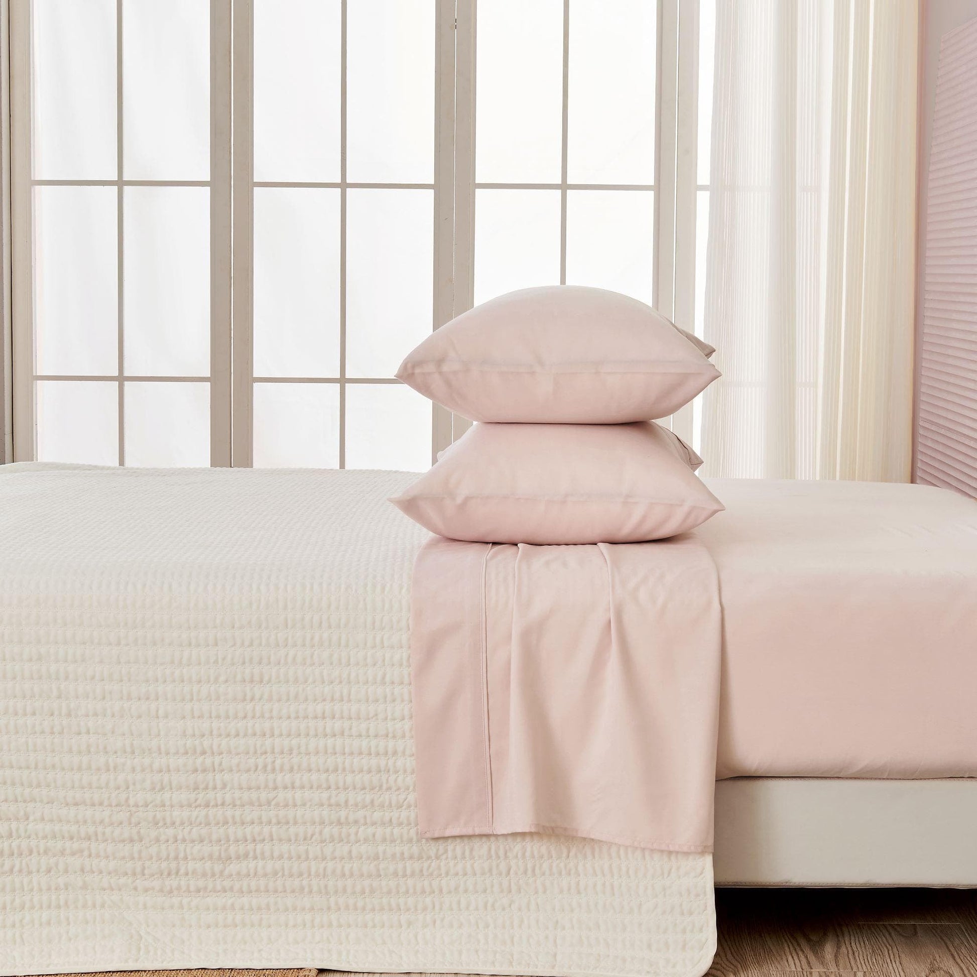 Pink bedding set on a bed with a neutral color scheme