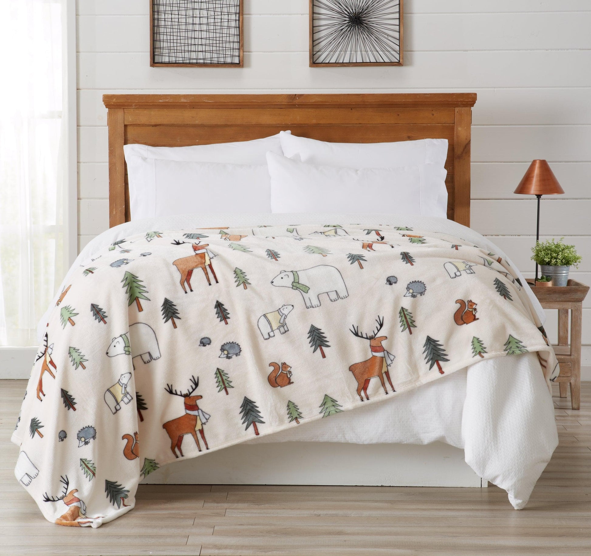 Bed with wooden headboard and forest-themed comforter featuring animals and trees.