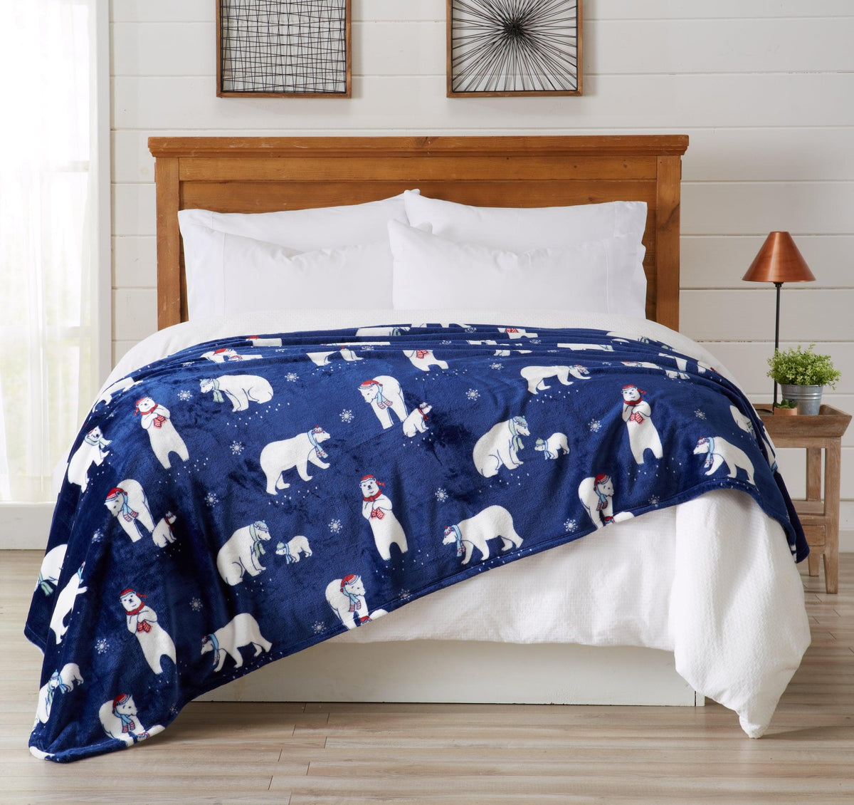 Blue blanket with polar bear pattern draped over a bed in a bedroom setting.