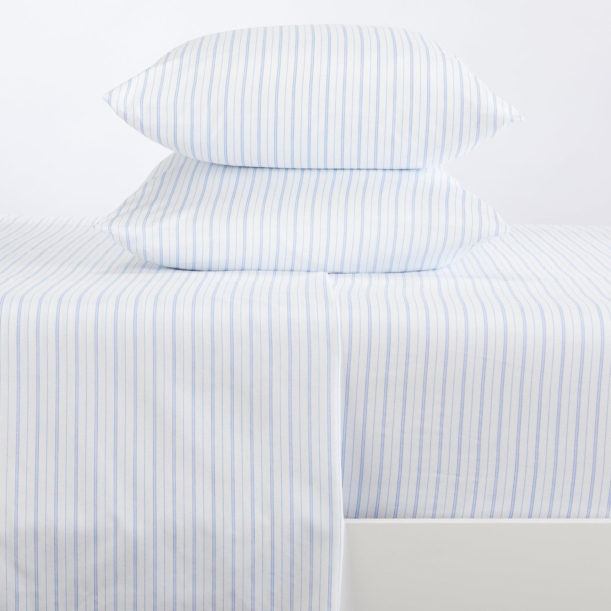 Striped bed sheets and pillowcases on a bed with a white background