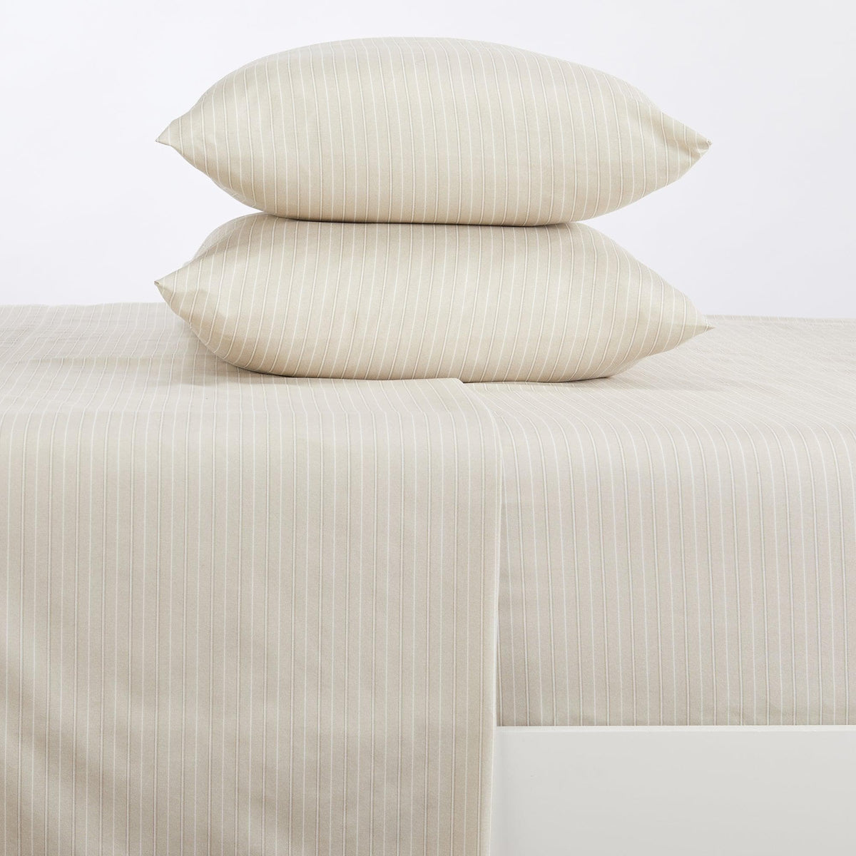 Beige striped bed sheets and pillows on a white background