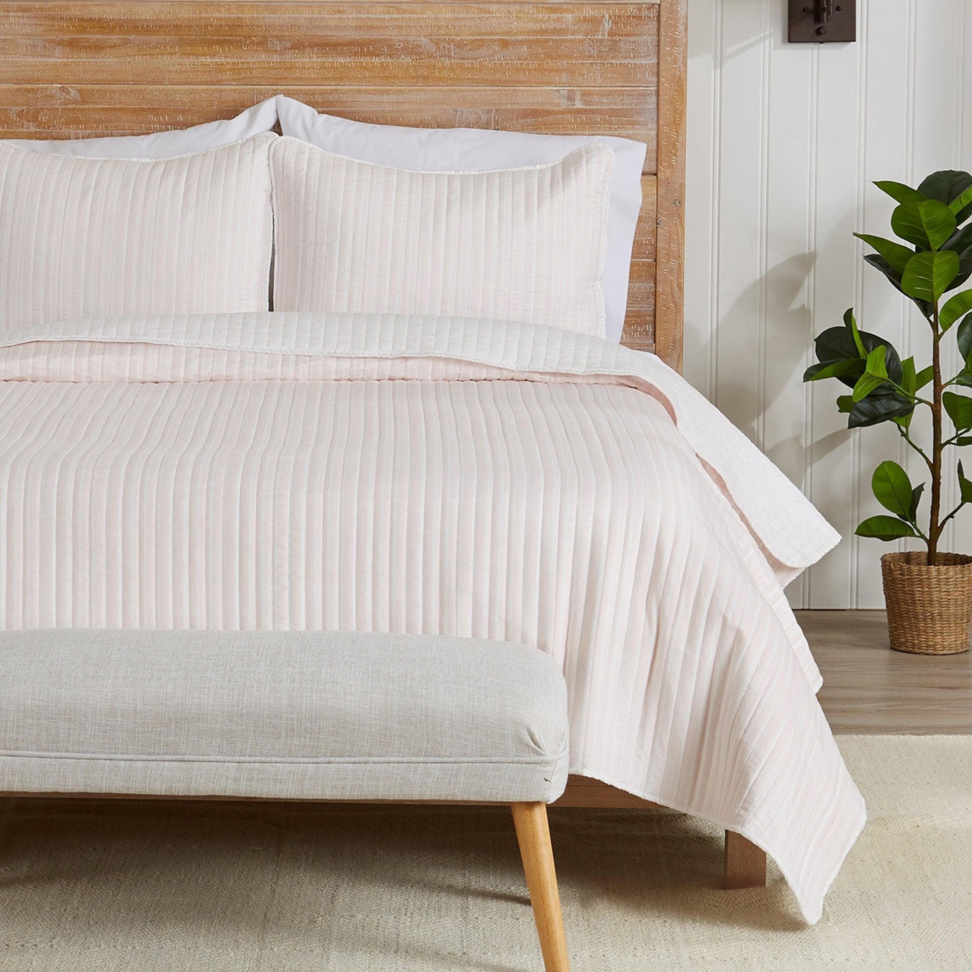 Neatly made bed with striped bedding in a bedroom setting.
