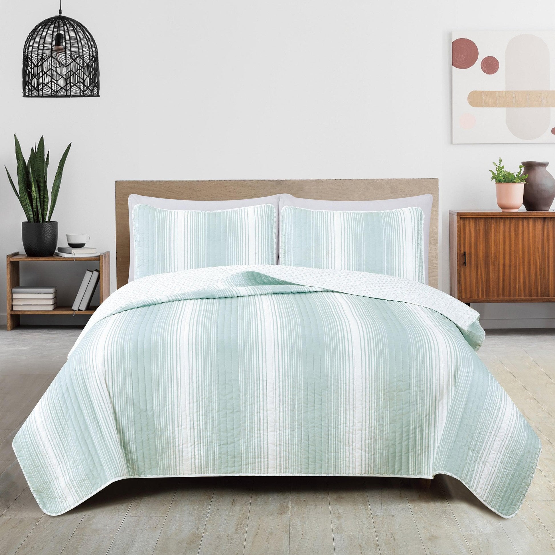 Teal striped quilt set on a bed in a bedroom setting with decor elements.