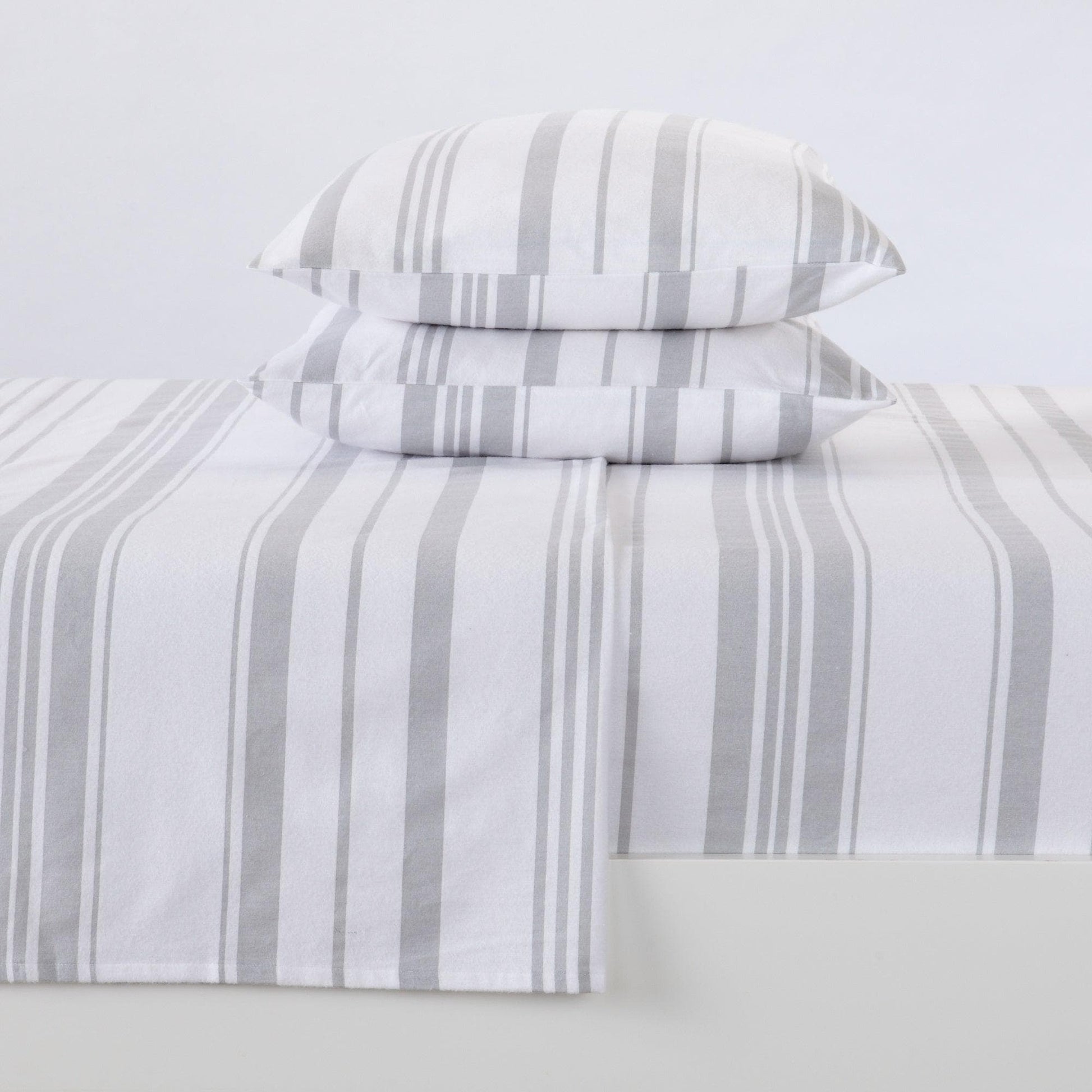 Striped bed sheet set with matching pillowcases on a light gray background