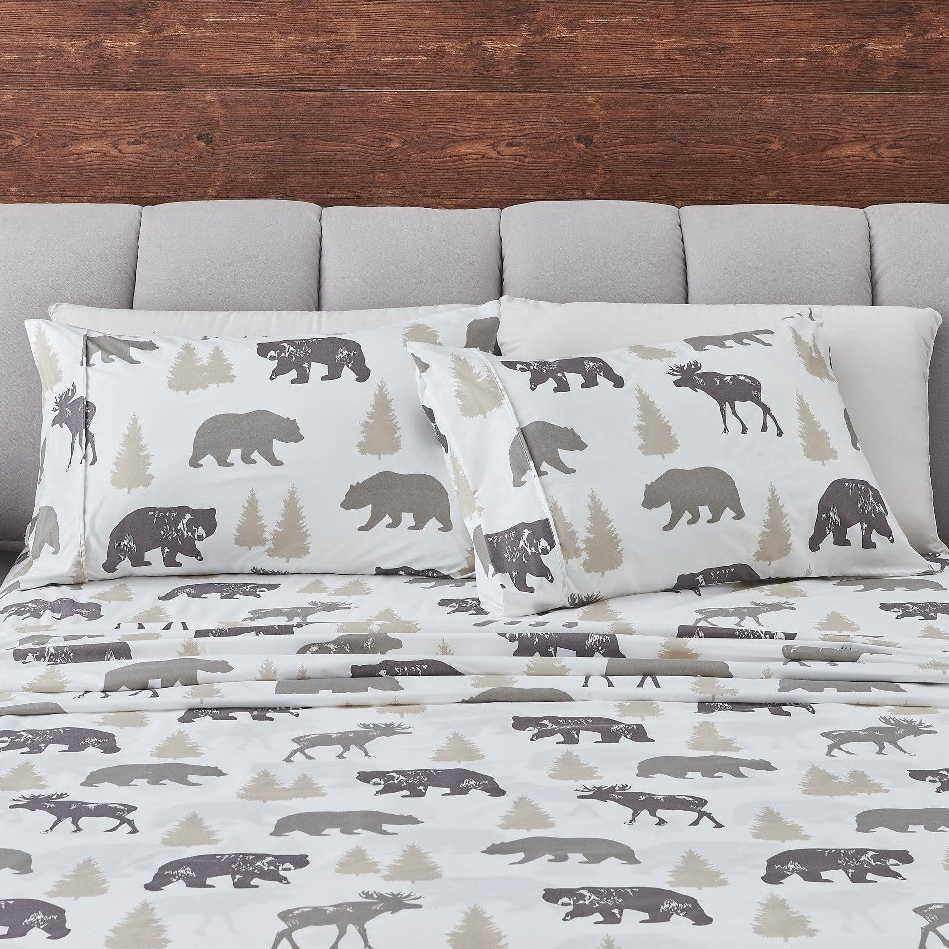 Bedding set with bear and moose pattern on a bed with gray headboard.