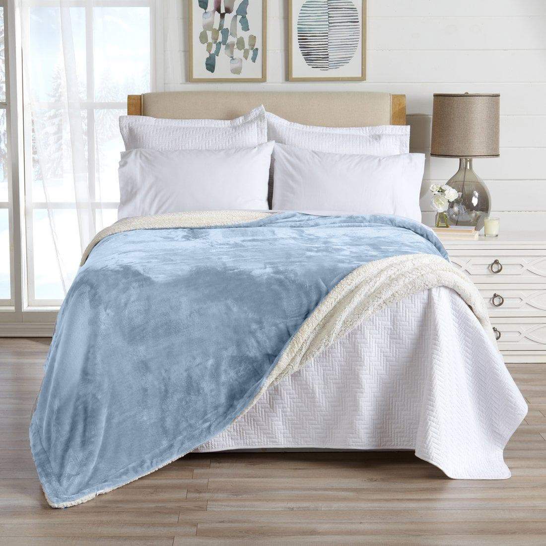 Blue and white blanket on a bed in a bedroom setting