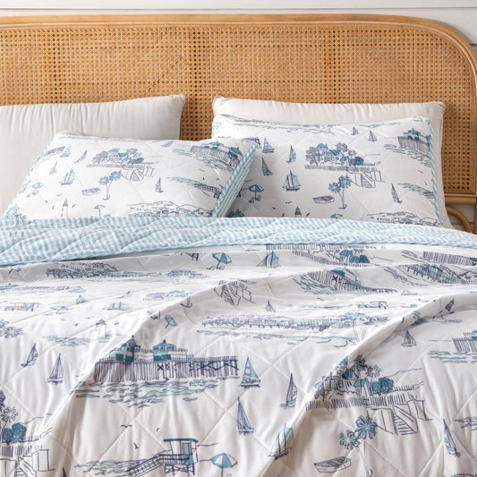 Bed with nautical-themed bedding featuring boats and lighthouses on a white background.