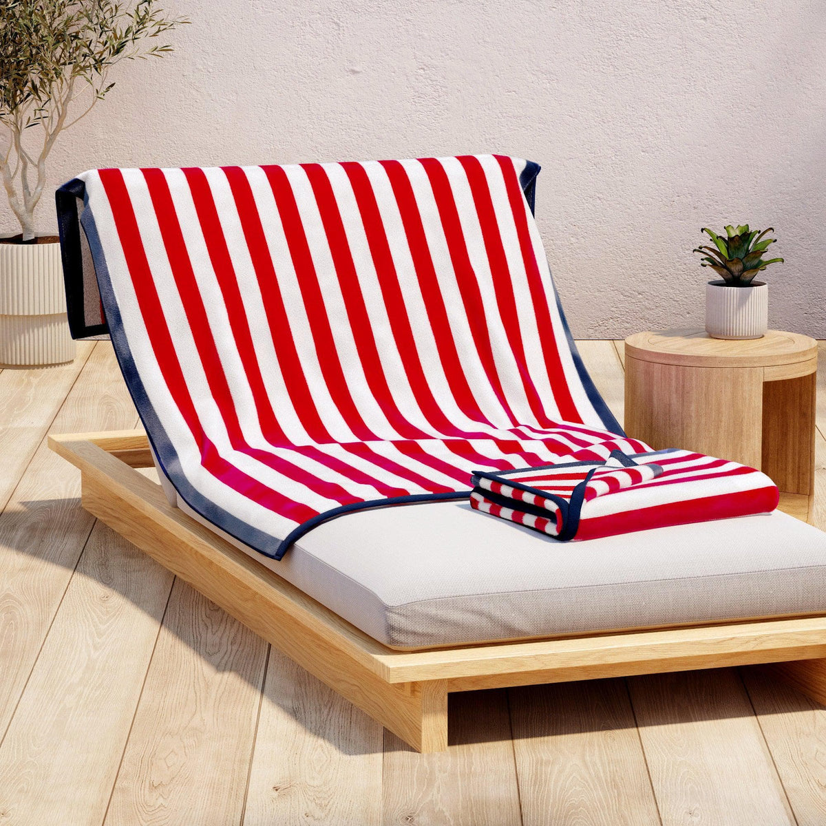 Red and white striped towel on a wooden lounge chair with a neutral background