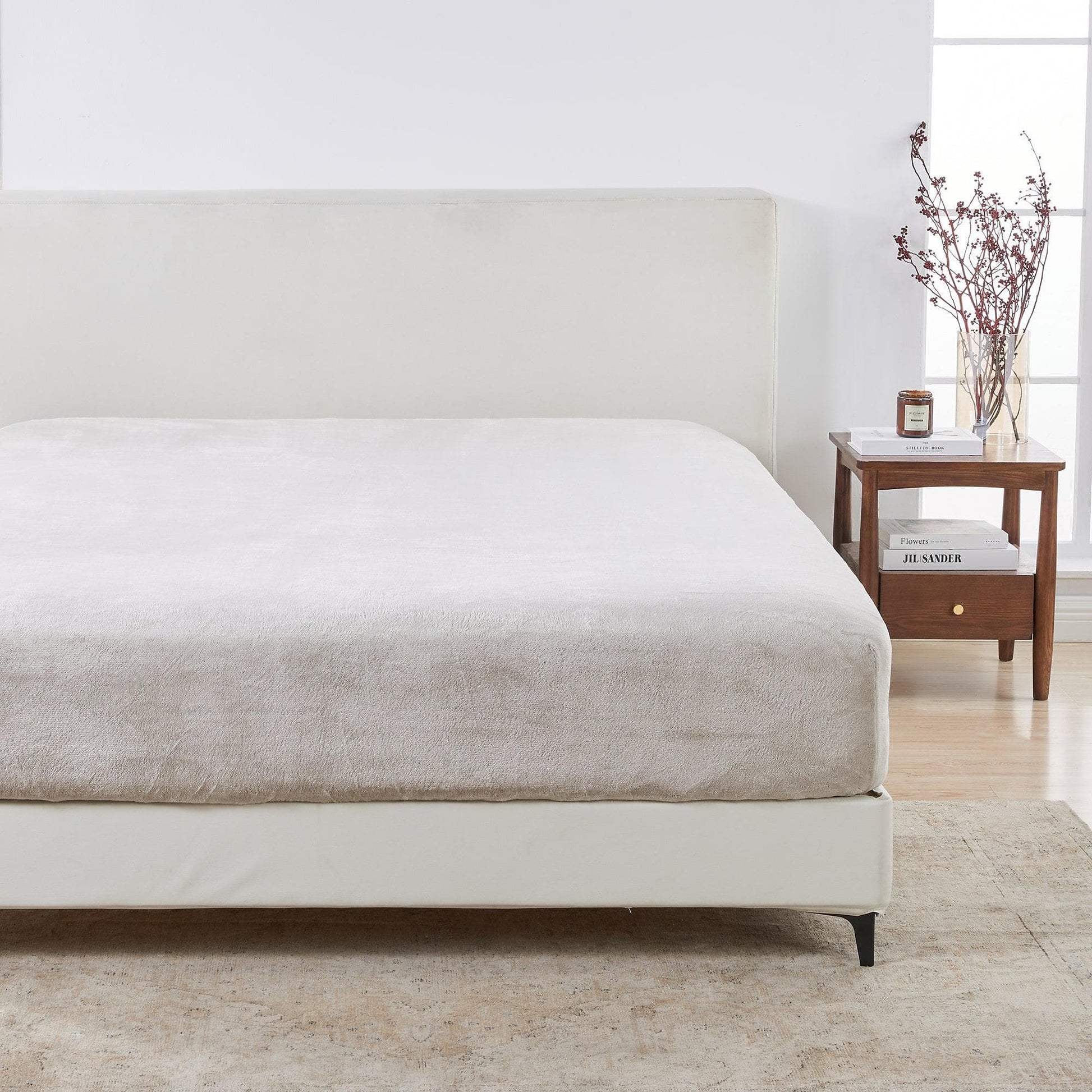 Neatly made bed with a wooden nightstand in a bright room