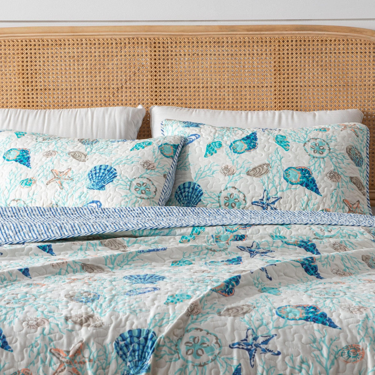 Bed with a floral patterned quilt and pillows against a wooden headboard.
