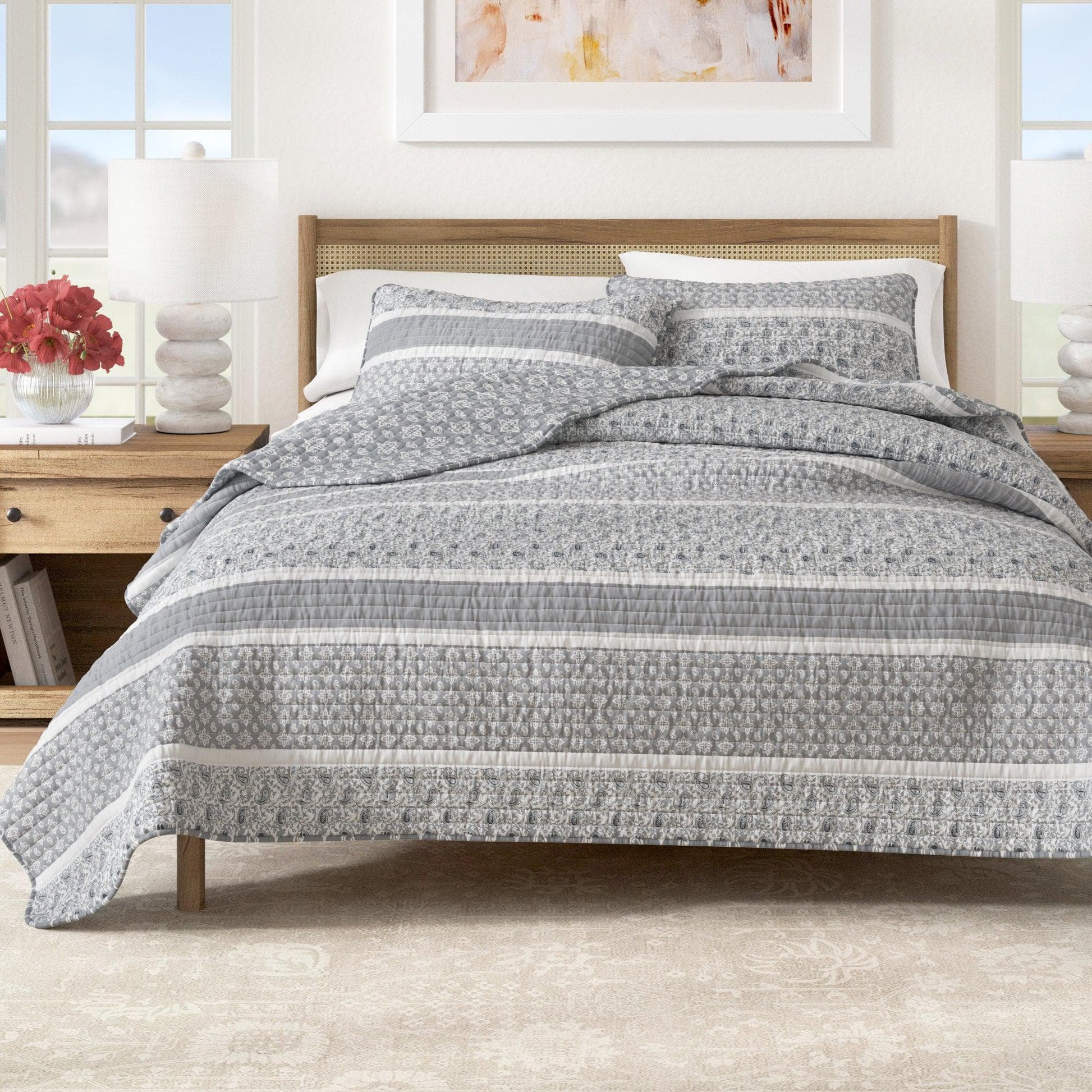 Bed with gray and white patterned comforter in a bright bedroom setting