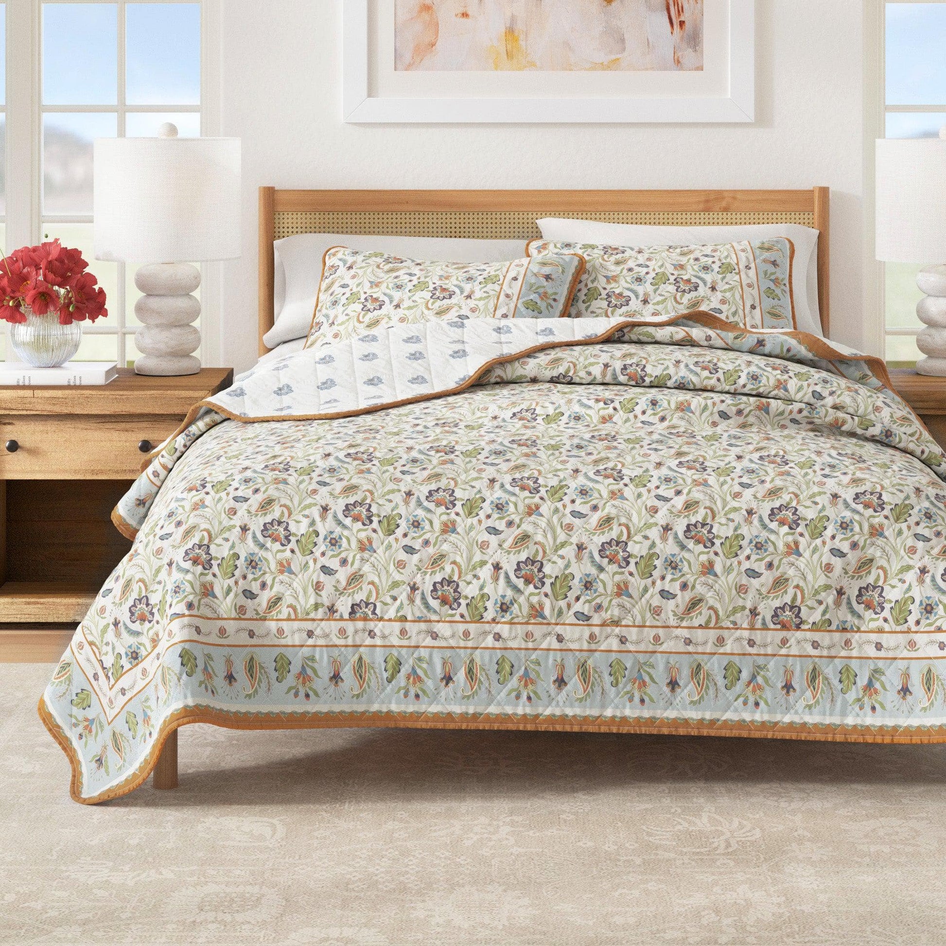 Floral patterned quilt on a bed in a well-lit bedroom