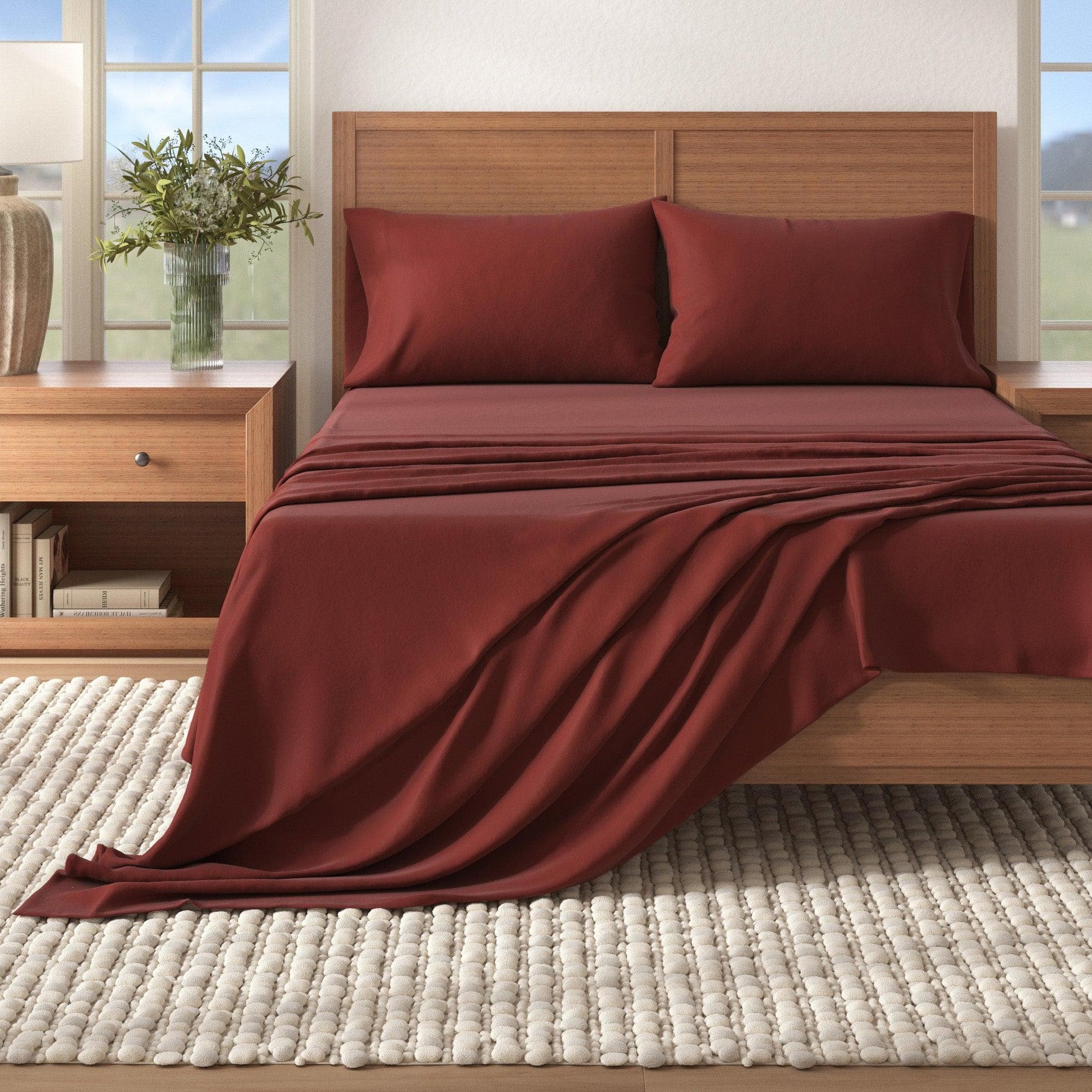 Bed with red bedding and wooden headboard in a bright bedroom.