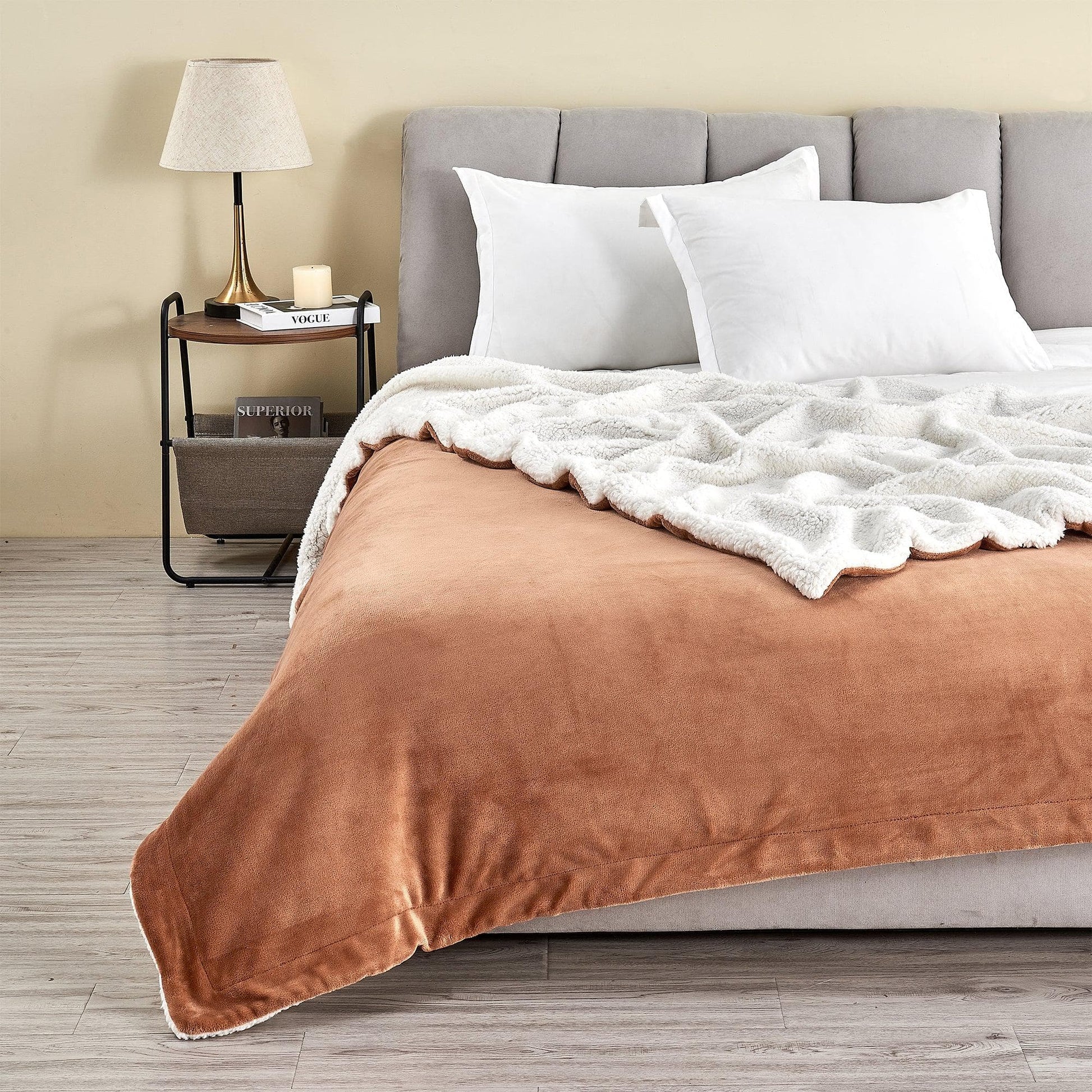 Bedroom with a bed featuring brown comforter and white pillows, nightstand with lamp and books.