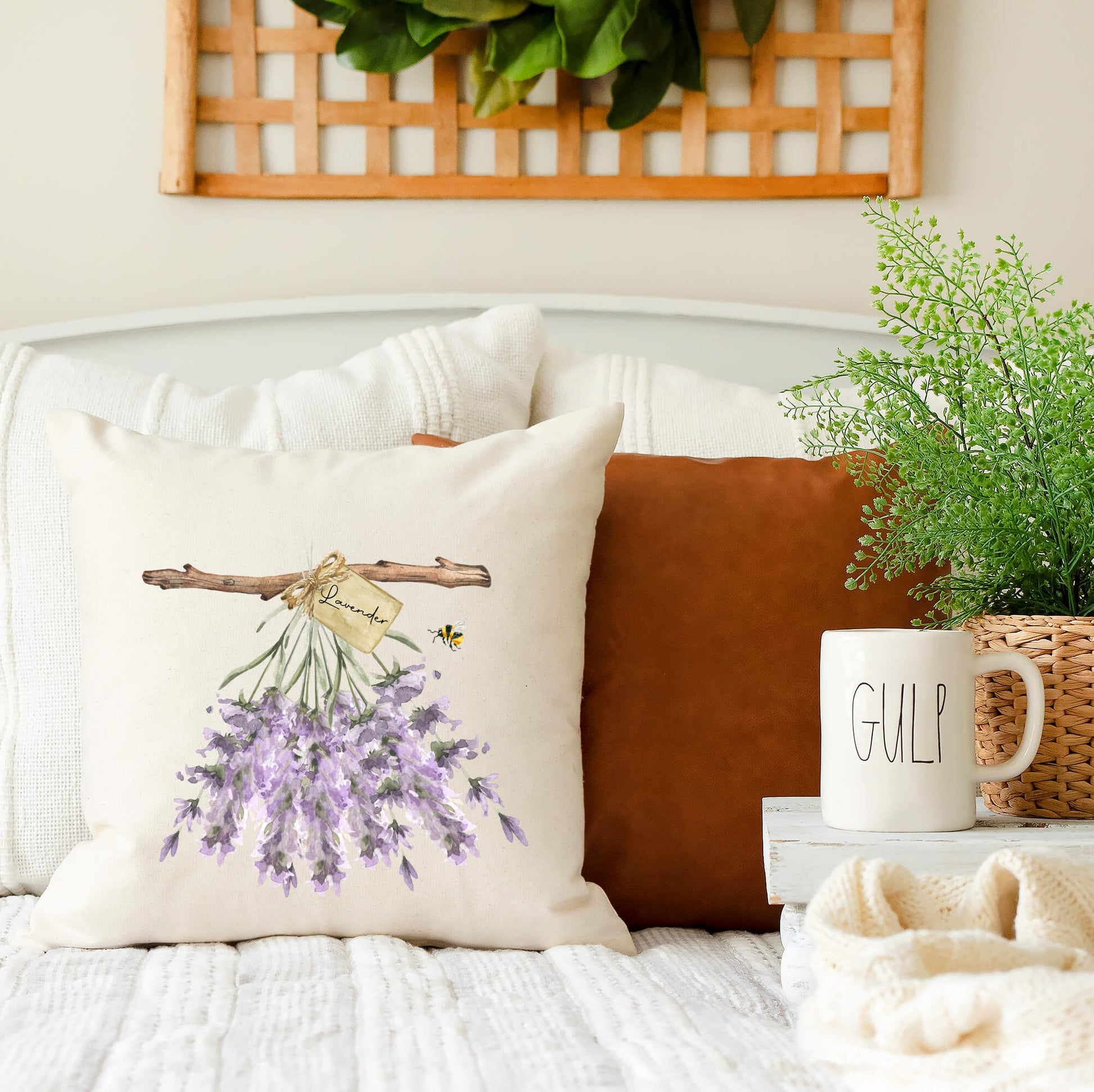 Hanging Lavender Spring Pillow Cover on a couch with a rustic decor, showcasing muted lavender flowers and a bee.