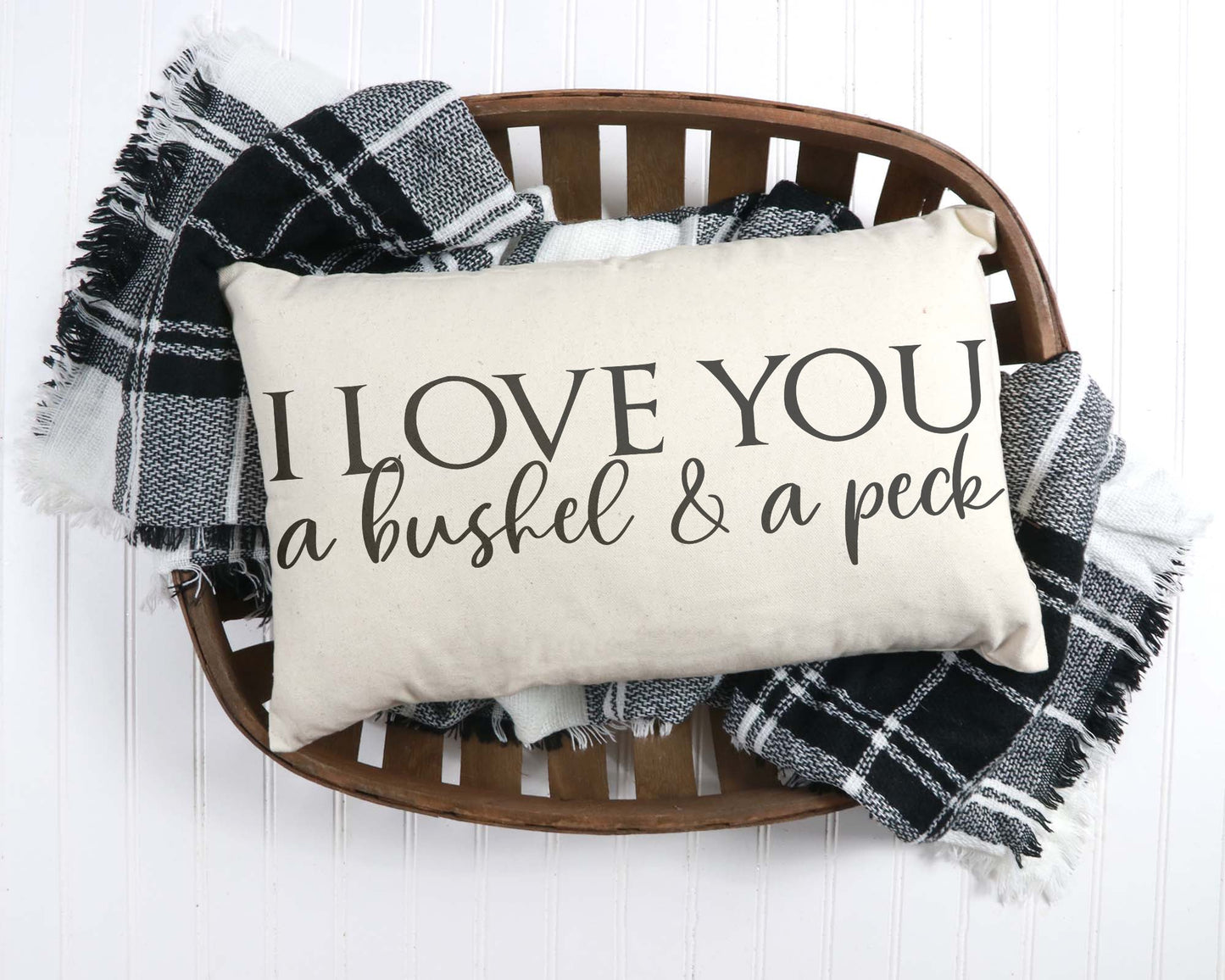 I Love You A Bushel and A Peck 12x20 inch Pillow Cover placed on a wooden tray with a checkered throw blanket.