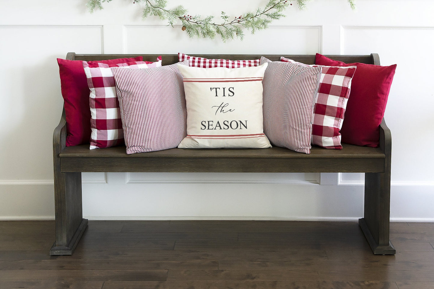 Tis the Season Red Farmhouse Stripes 18x18 inch Pillow Cover displayed on a cozy wooden bench with festive pillows.