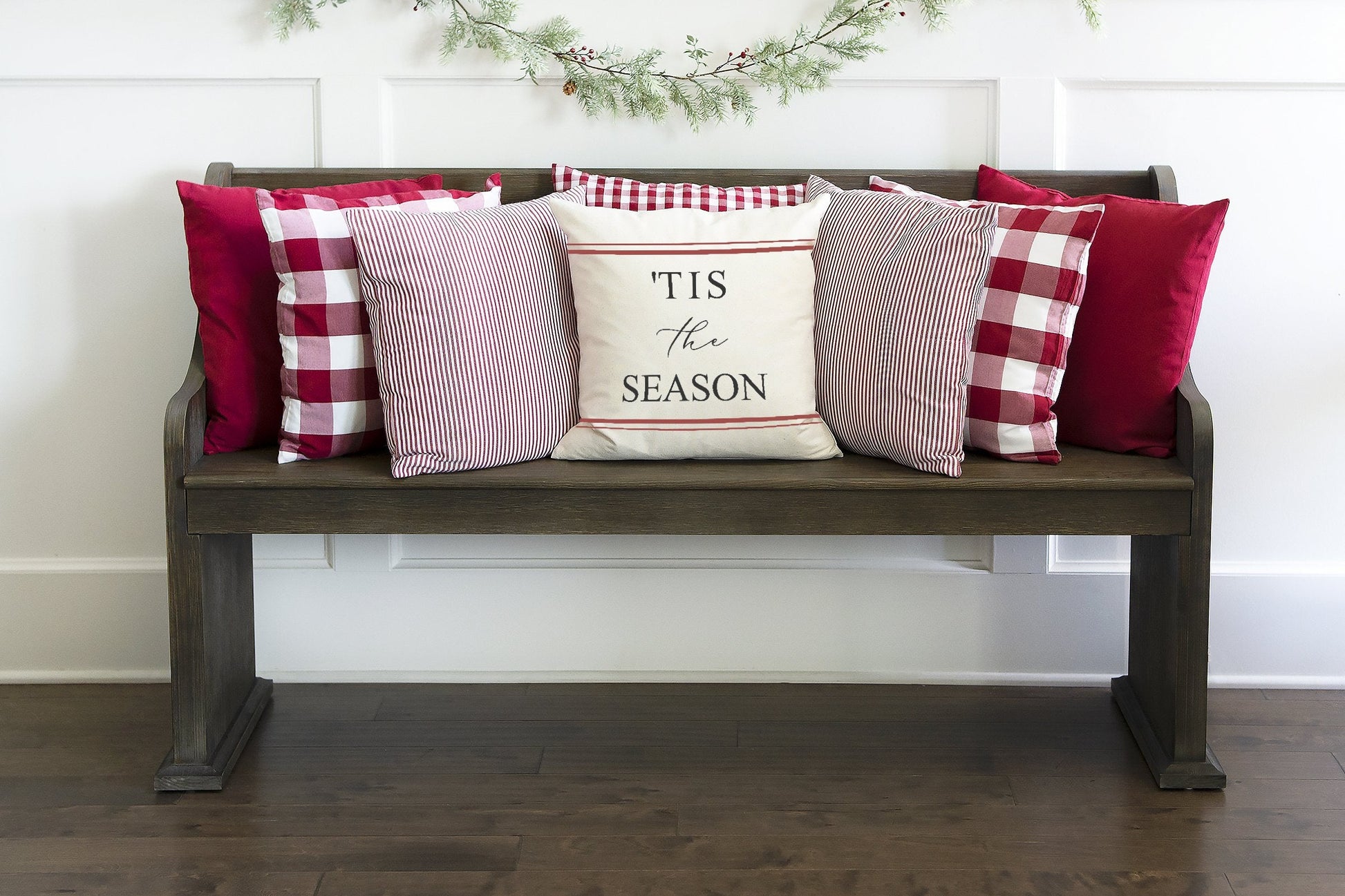 Tis the Season Red Farmhouse Stripes 18x18 inch Pillow Cover displayed on a cozy wooden bench with festive pillows.
