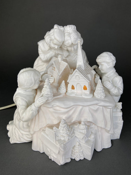 White ceramic nativity scene with two children and a church on a dark background