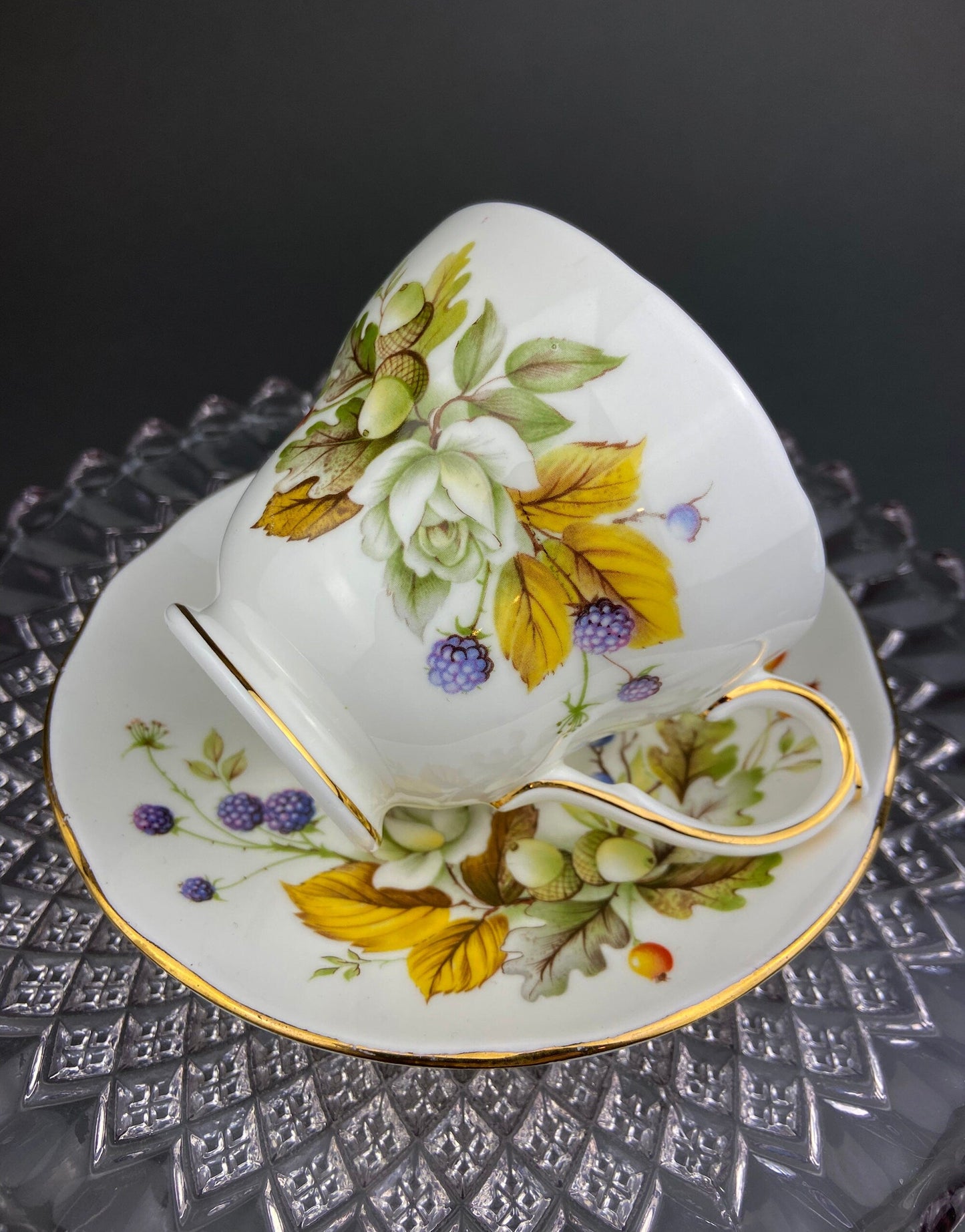 Decorative teacup and saucer with floral and leaf design on a textured surface.