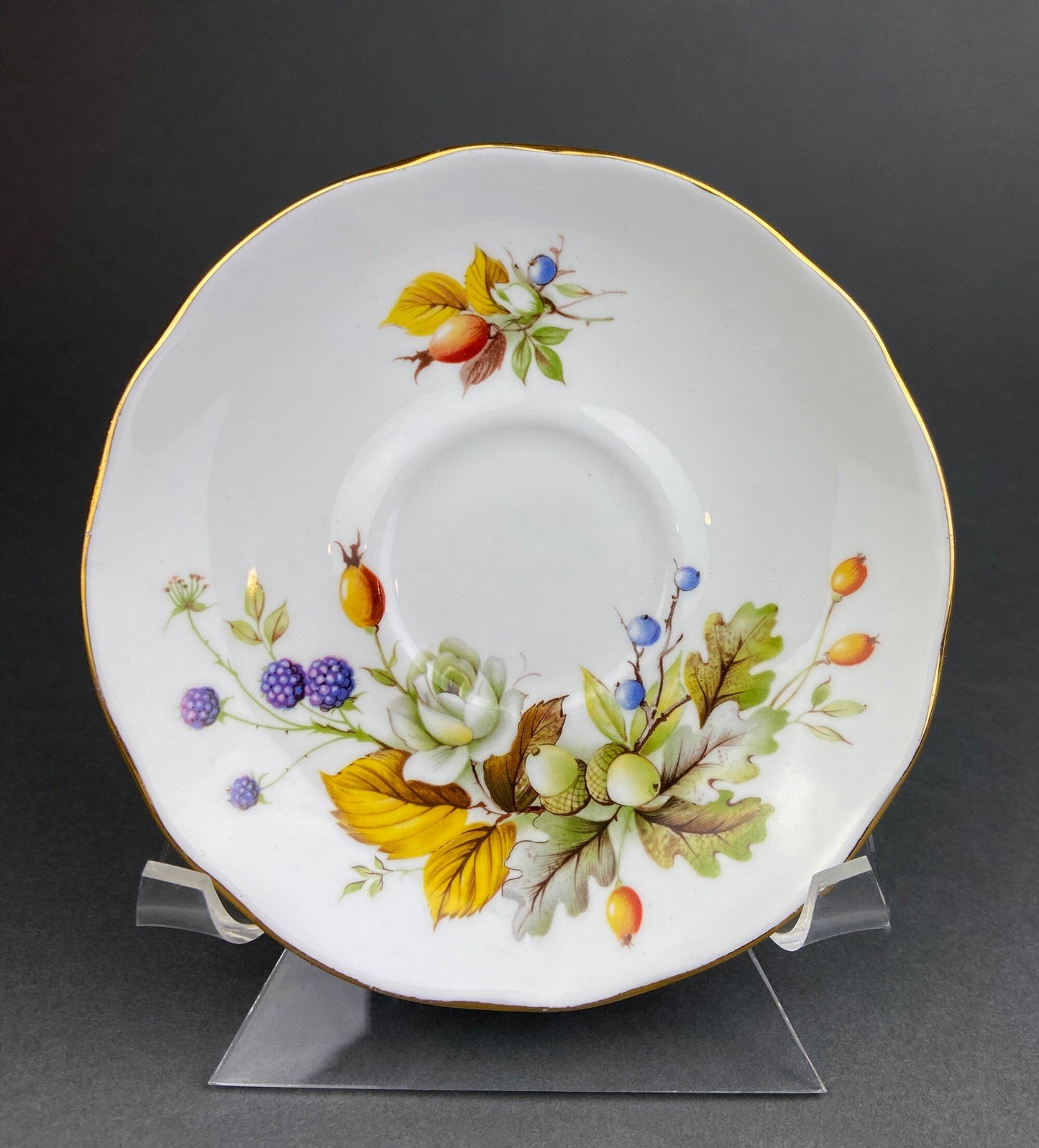 Decorative plate with floral and leaf patterns on a stand against a dark background