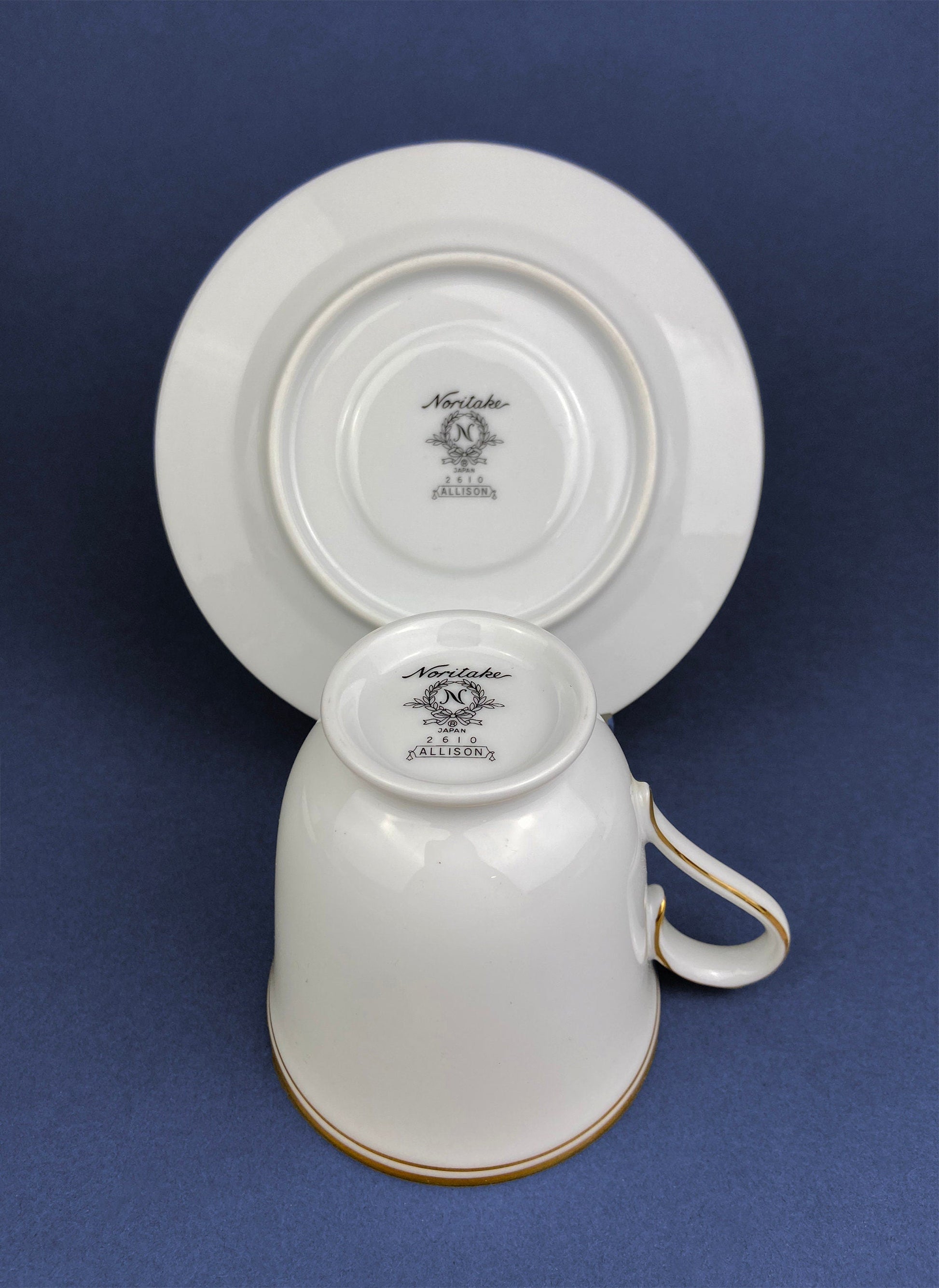 White ceramic cup and saucer with 'Noritake' branding on a blue background