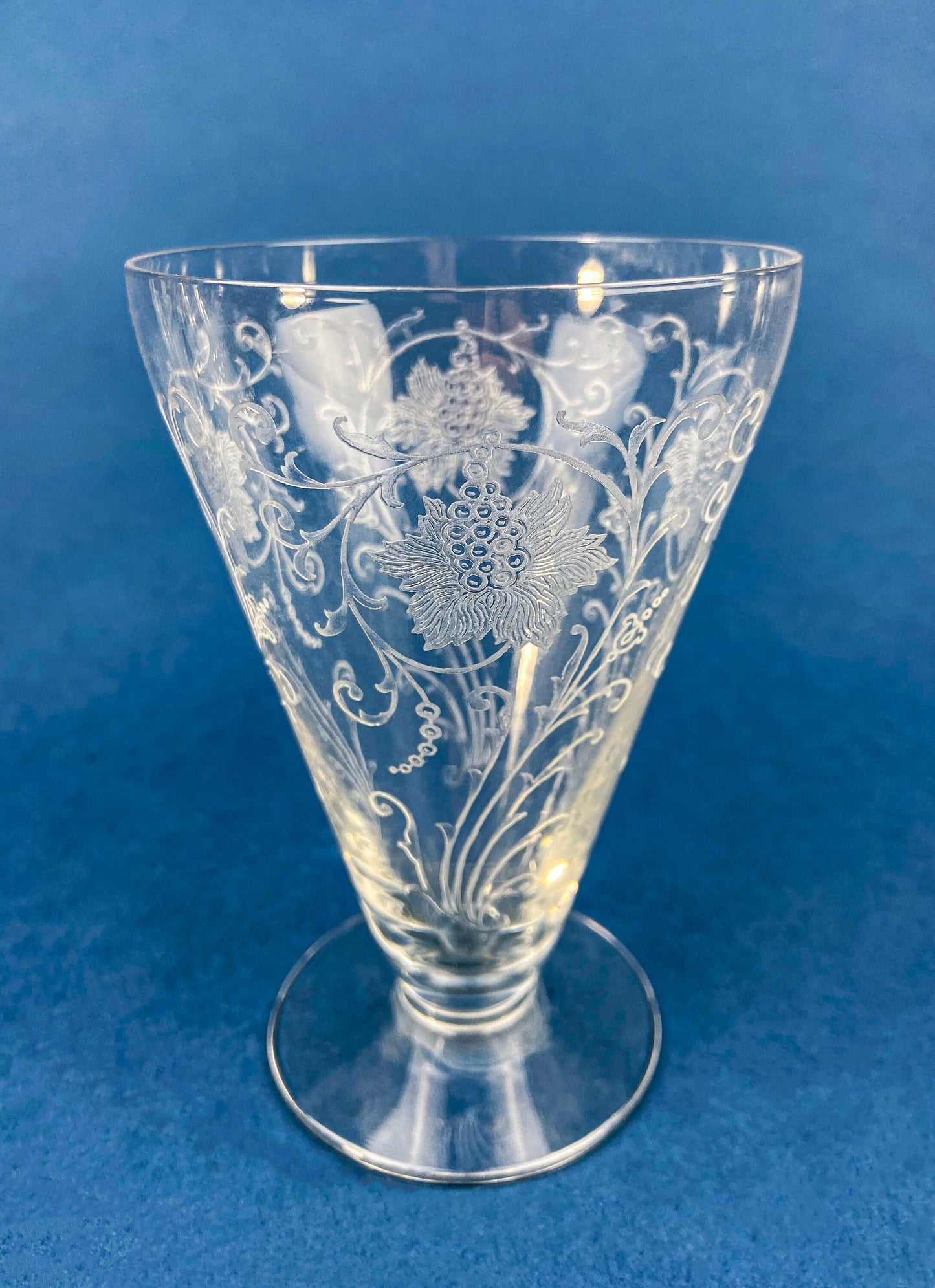Clear glass vase with floral etching on a blue background