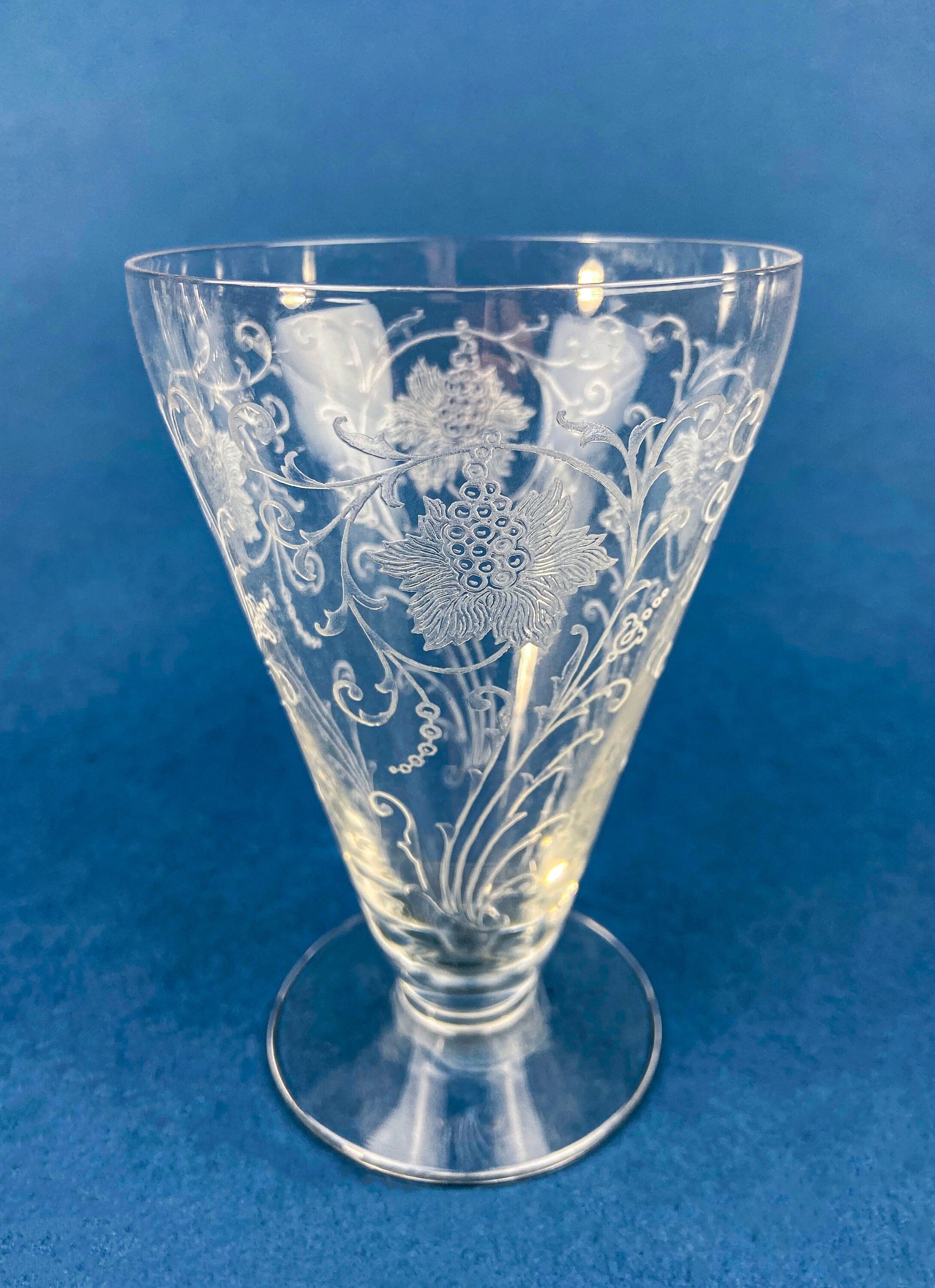 Clear glass vase with floral etching on a blue background