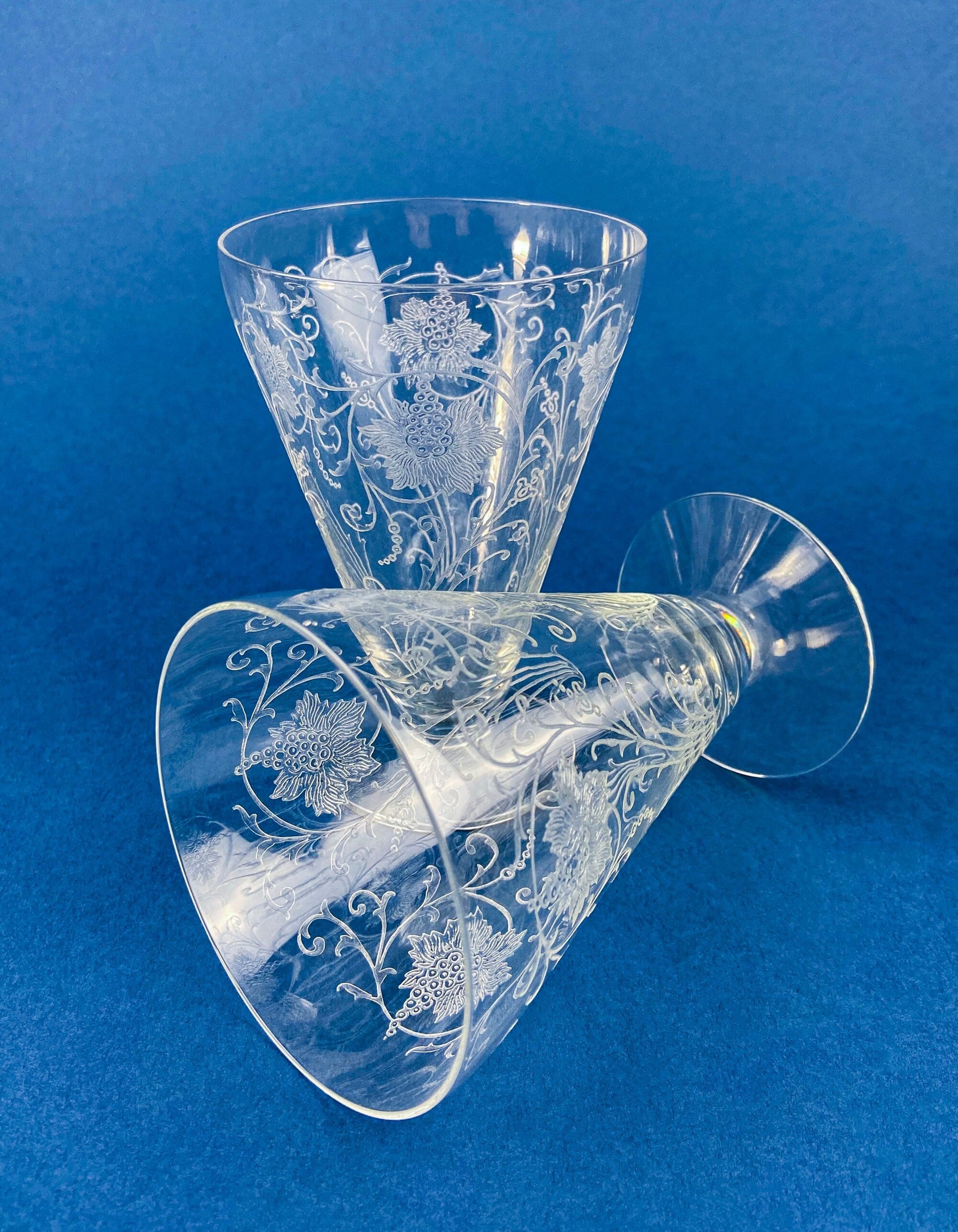 Two etched glass tumblers on a blue background