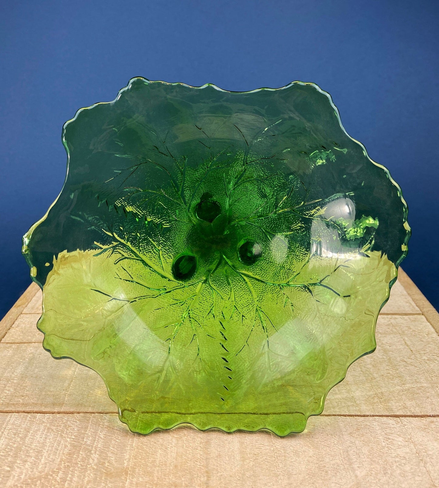 Green glass plate with textured surface on a wooden surface and blue background