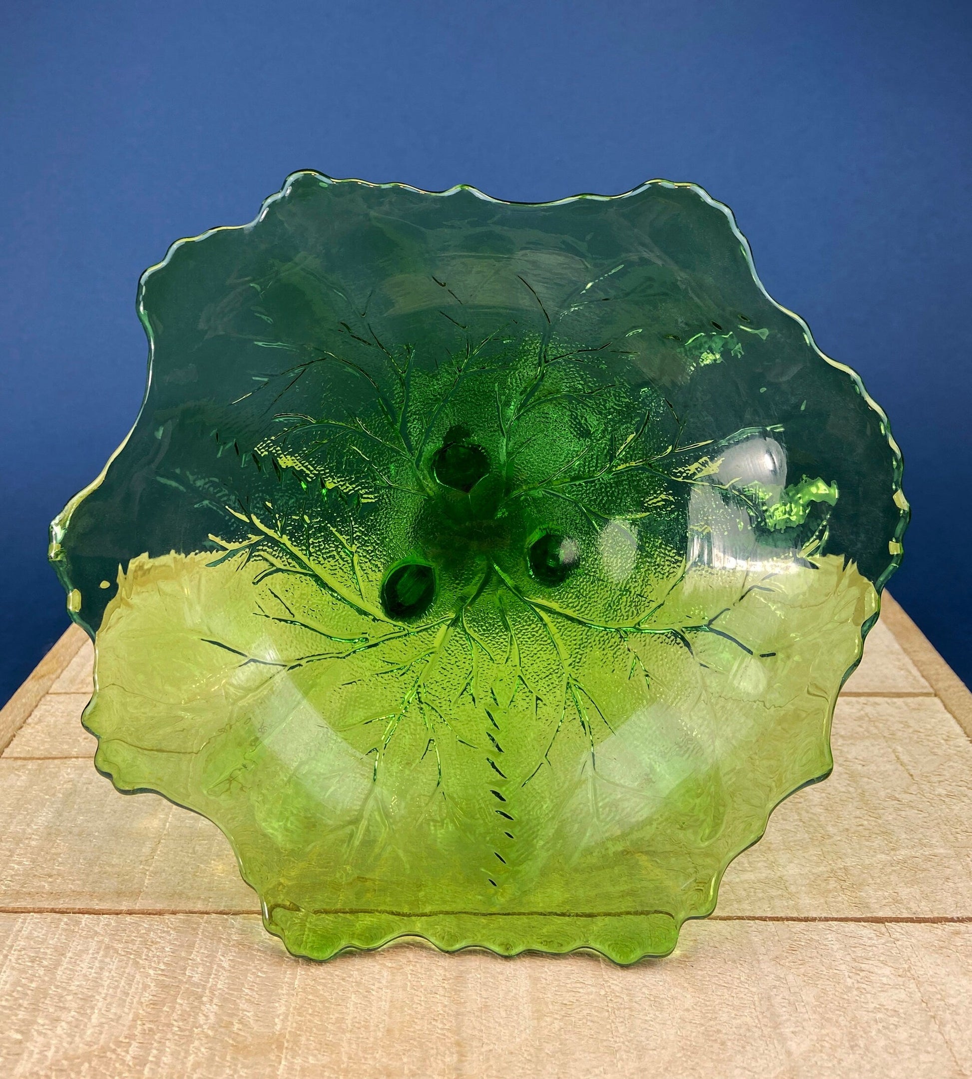 Green glass plate with textured surface on a wooden surface and blue background