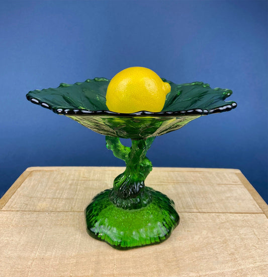 Green glass bowl with a lemon on a blue background