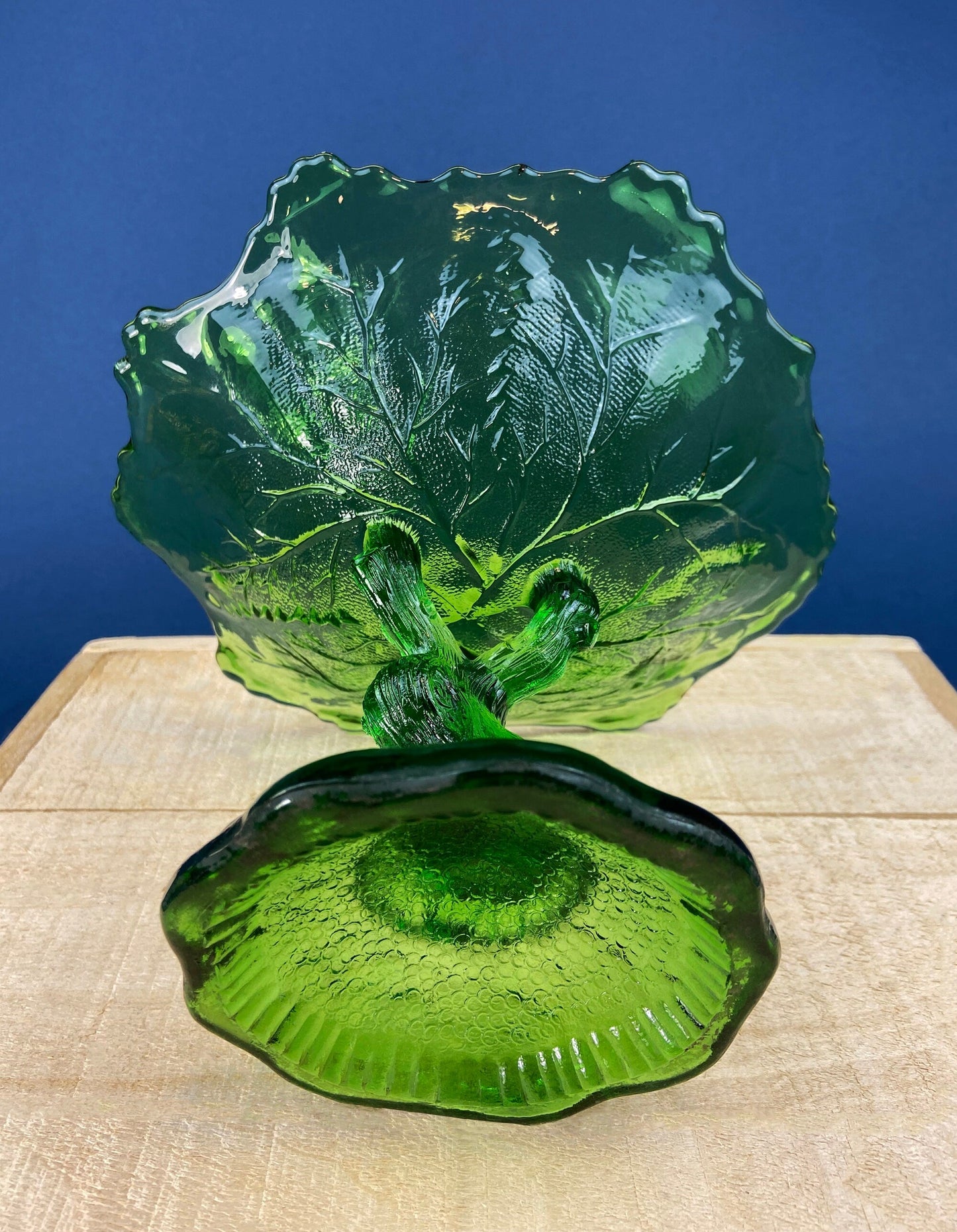 Green glass tree-shaped object on a wooden surface with a blue background