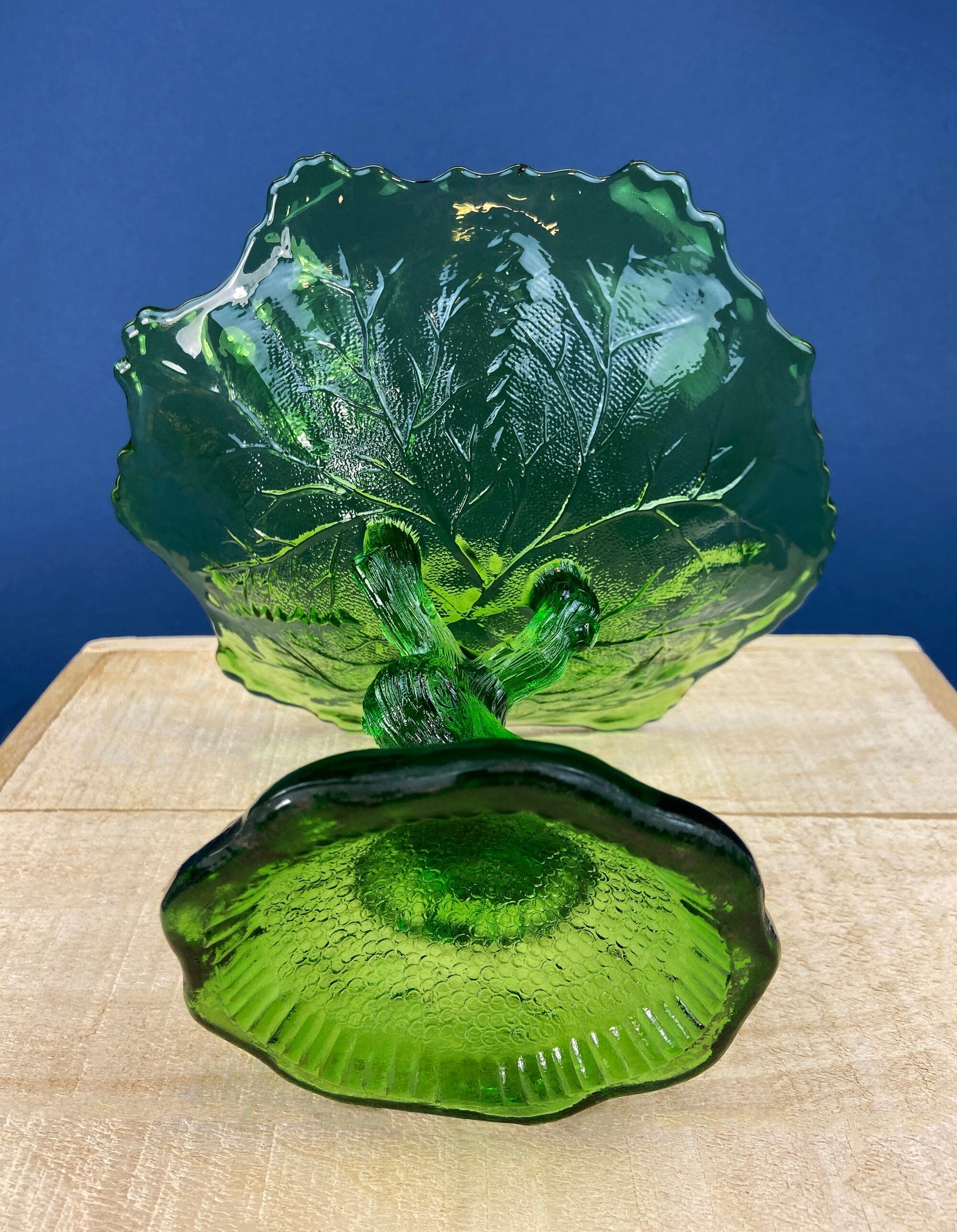 Green glass tree-shaped object on a wooden surface with a blue background