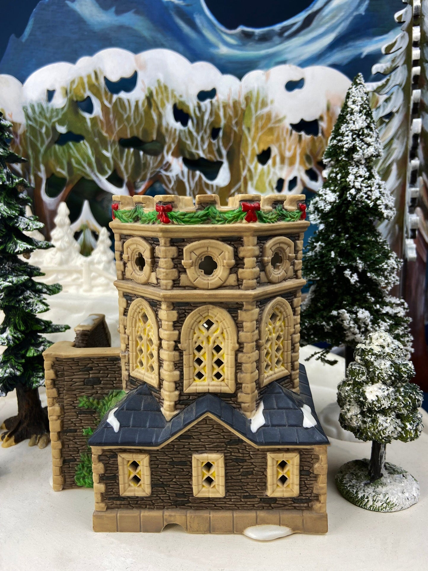 Decorative model of a castle with Christmas decorations against a snowy landscape background.