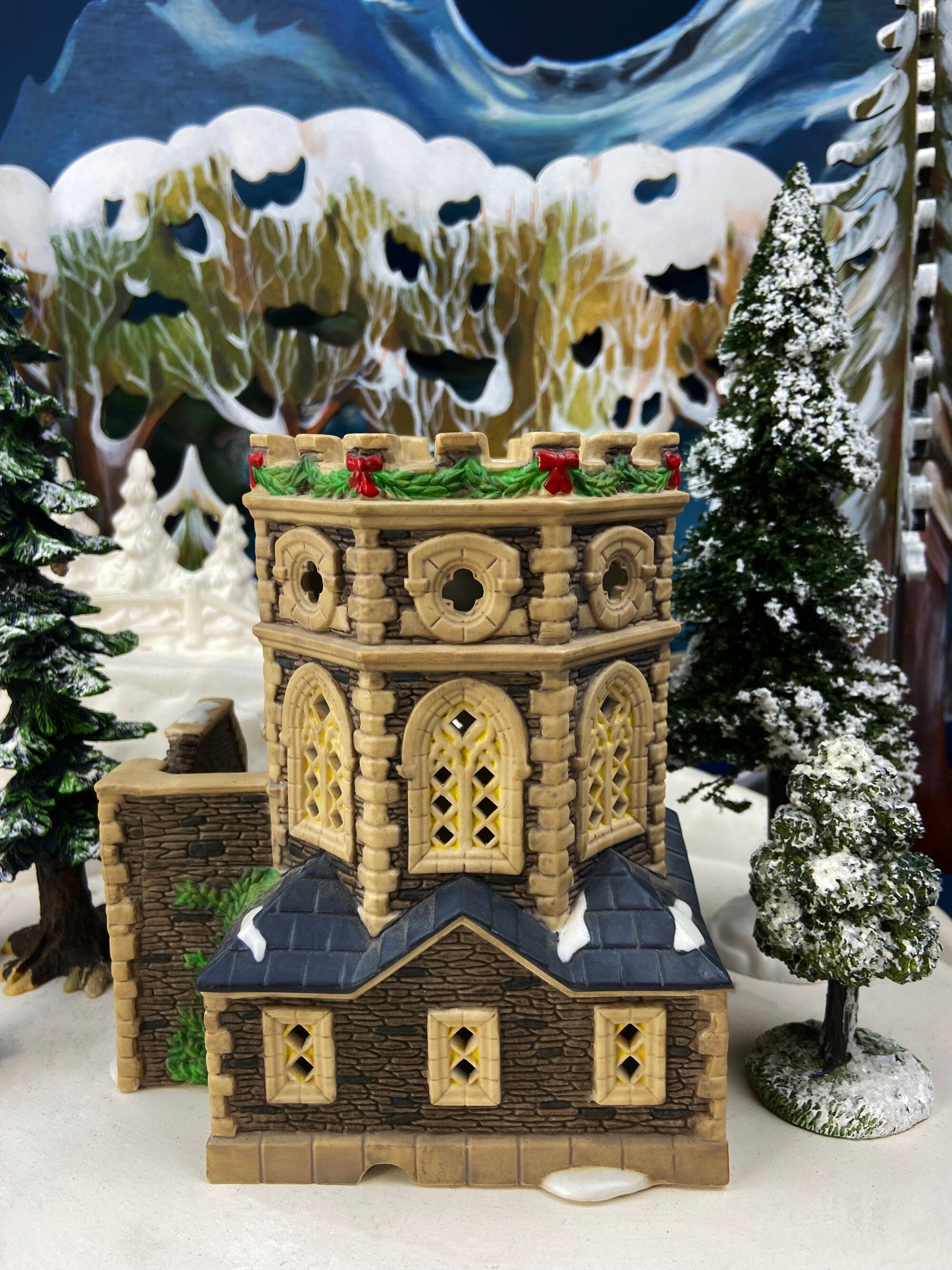 Decorative model of a castle with Christmas decorations against a snowy landscape background.