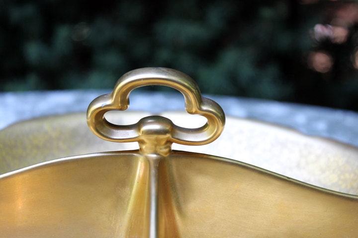 Close-up of a gold lid with a decorative handle on a metallic surface.