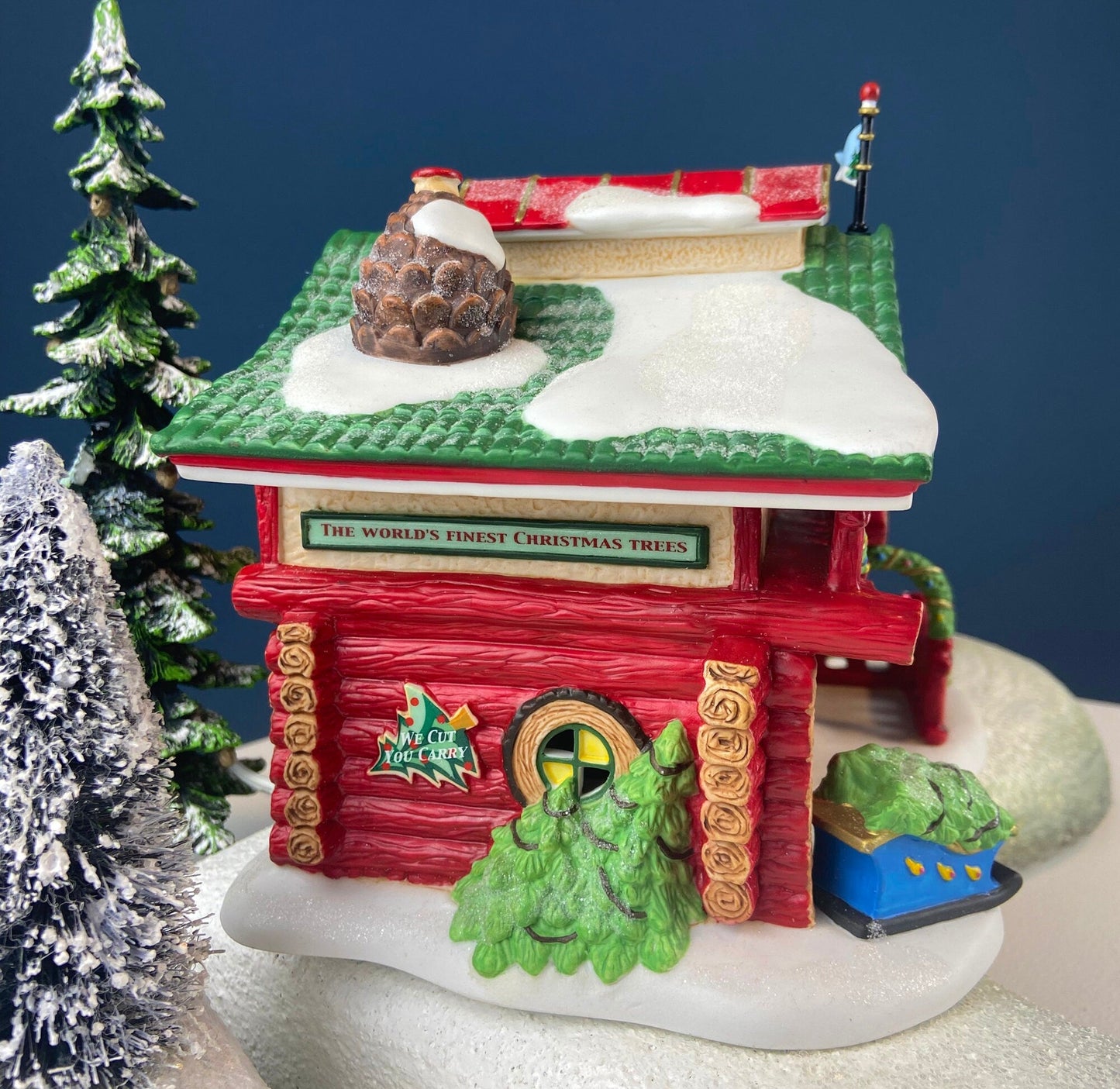 Decorative Christmas scene with a red building, trees, and snow on a blue background