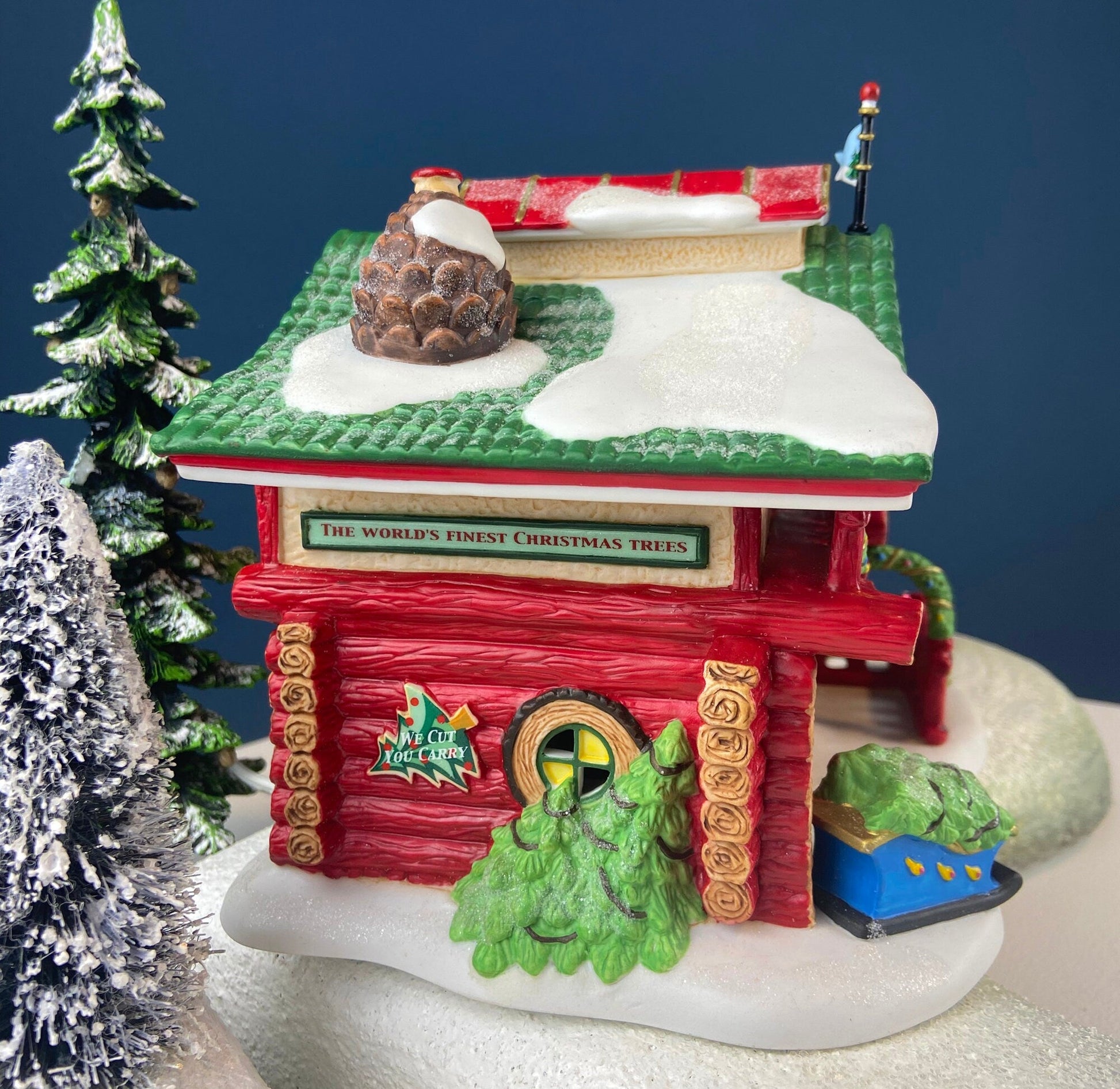 Decorative Christmas scene with a red building, trees, and snow on a blue background