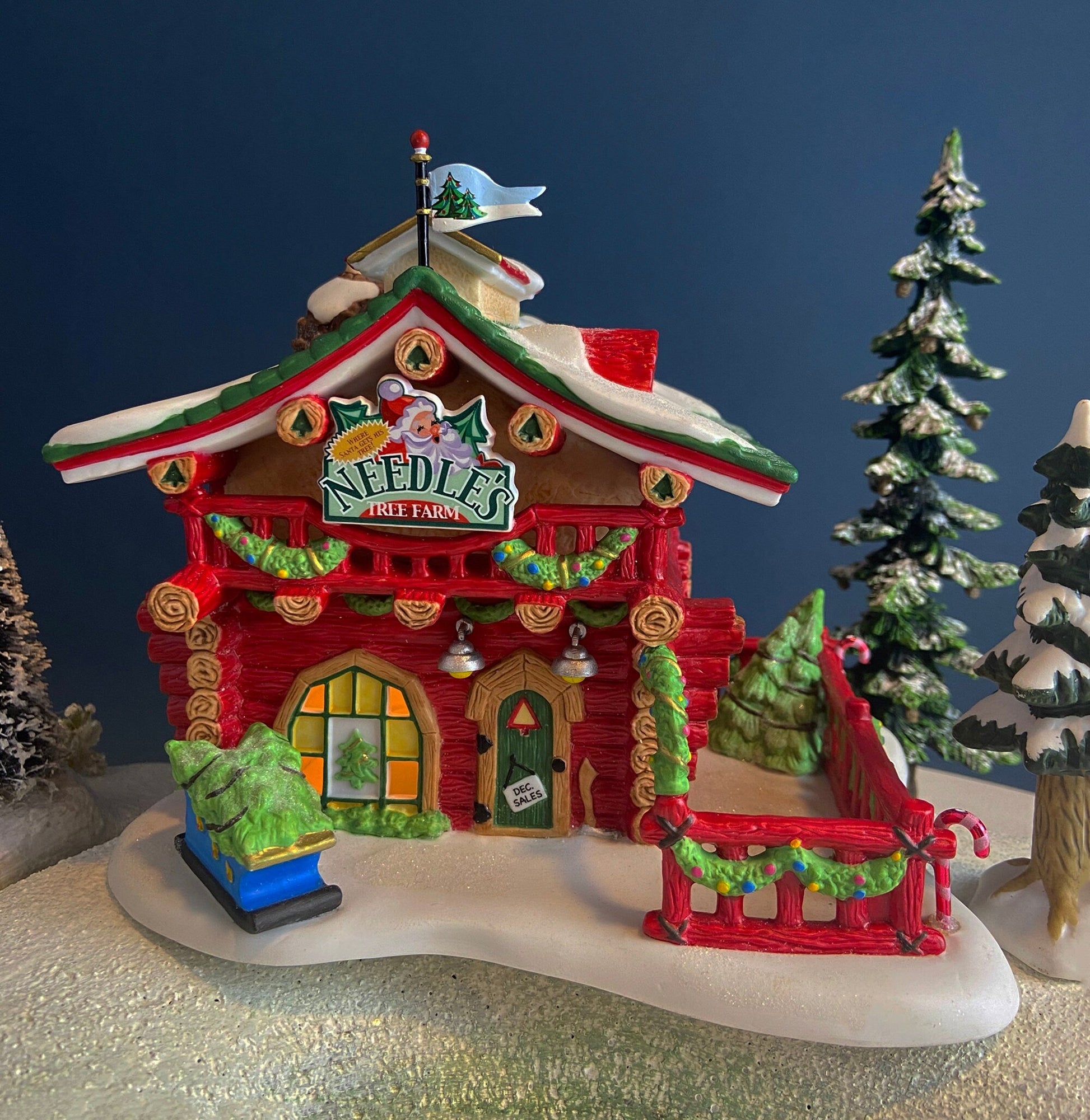 Decorative Christmas tree farm house ornament with trees and snow on a dark blue background