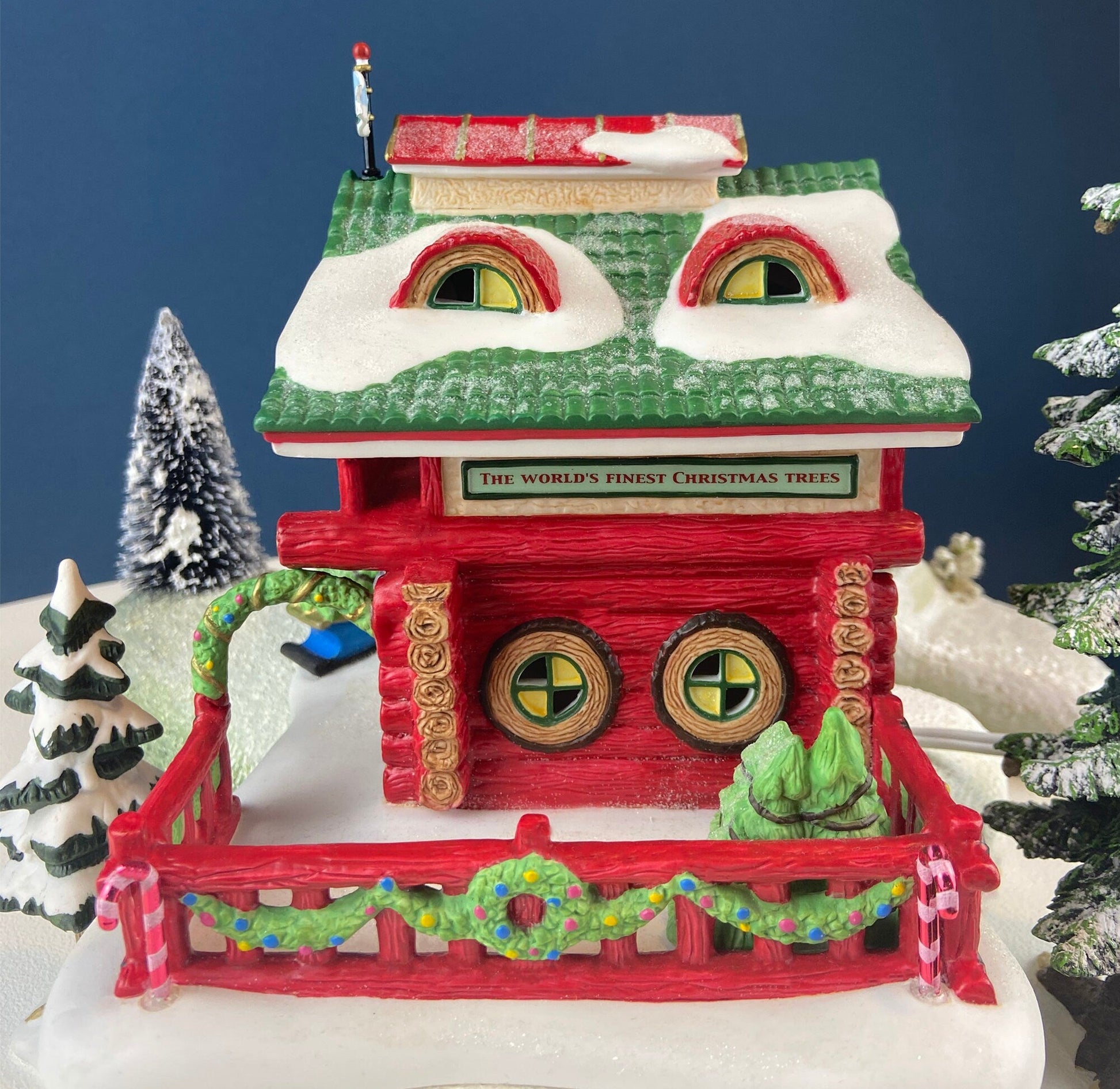Decorative Christmas scene with a red house, green trees, and snow on a blue background