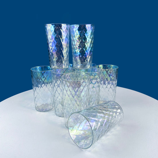 Set of iridescent glass tumblers on a white surface with a blue background